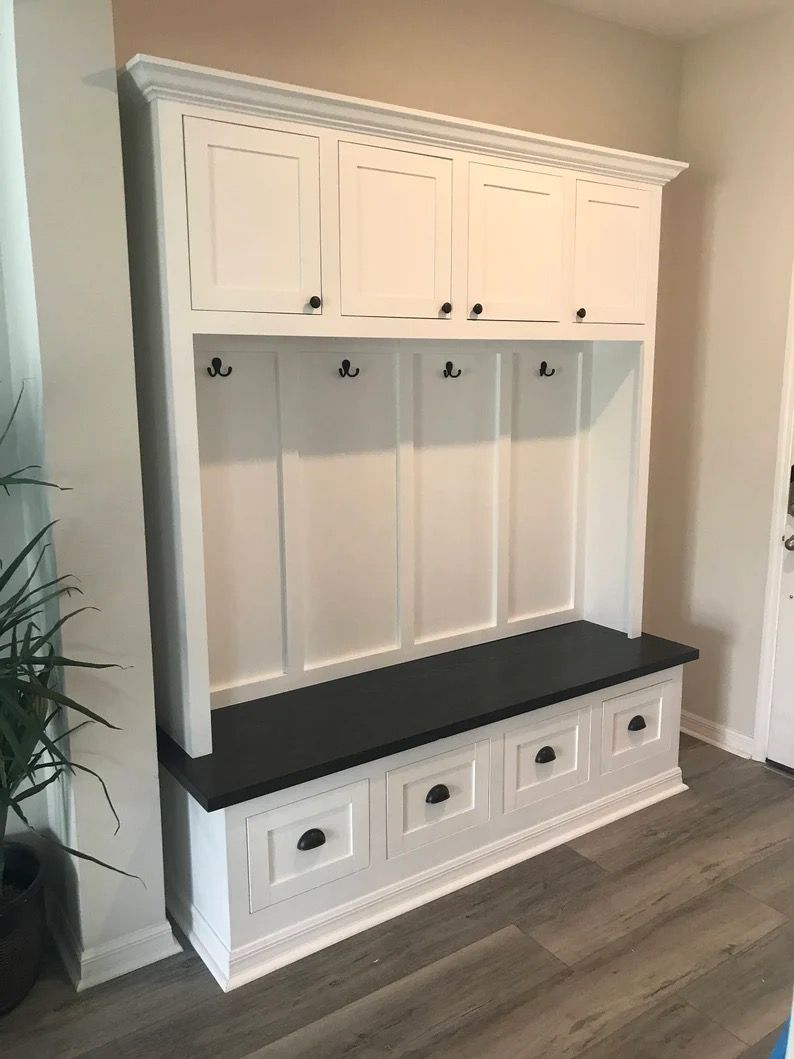 A white cabinet with a black bench and drawers in a living room.