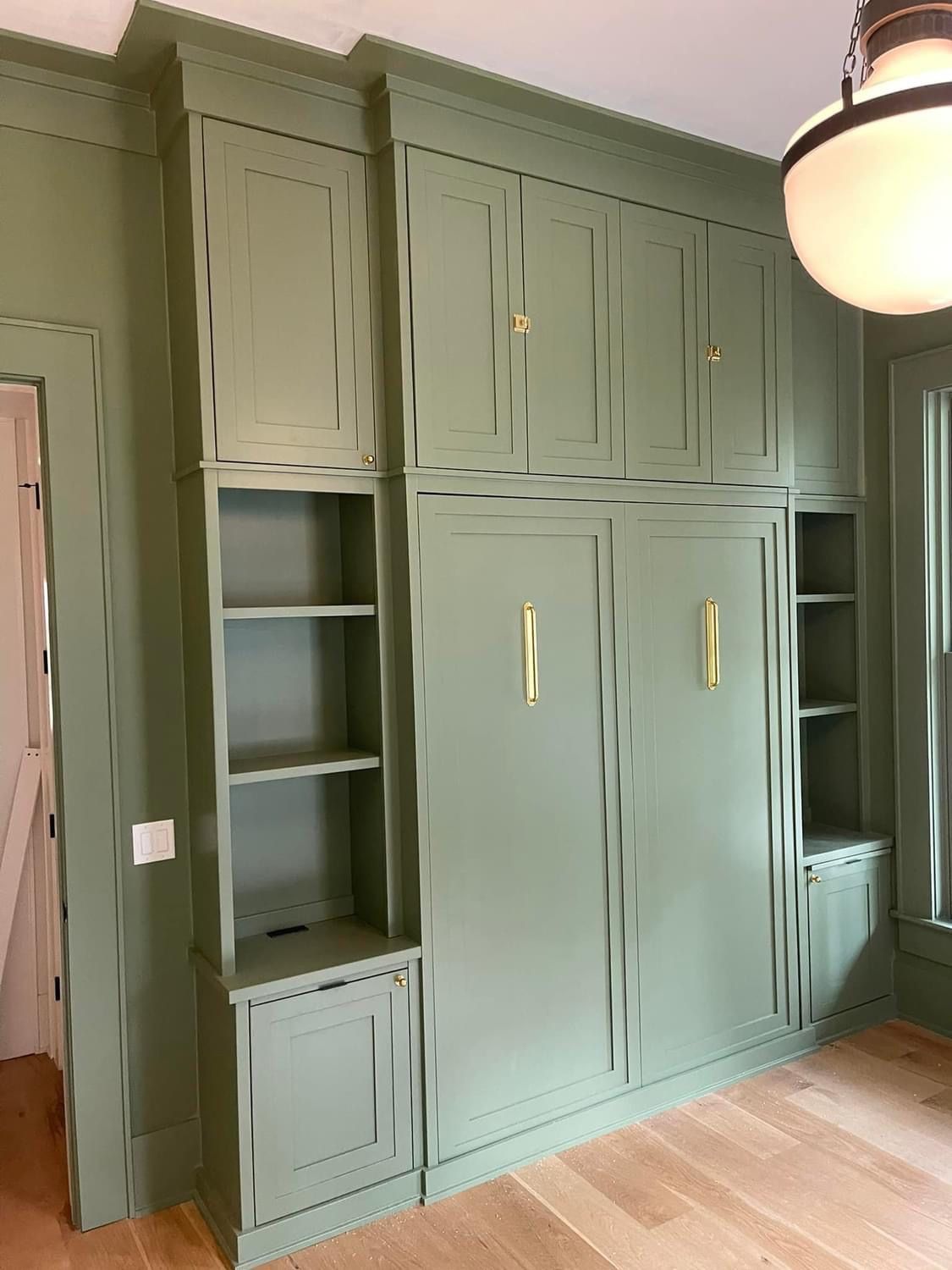 A room with green cabinets and shelves and a ceiling light.