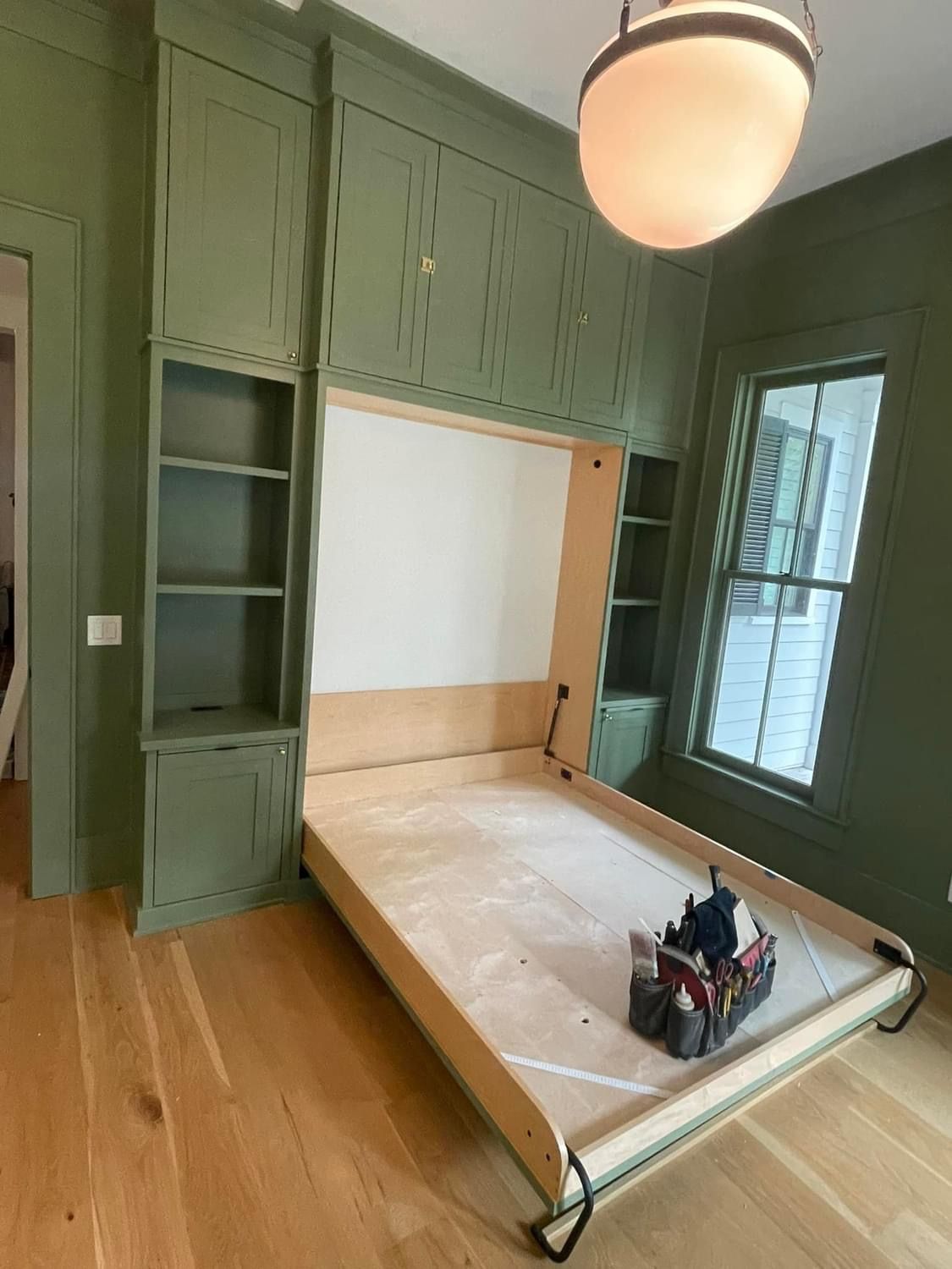 A bed is being built in a room with green walls.