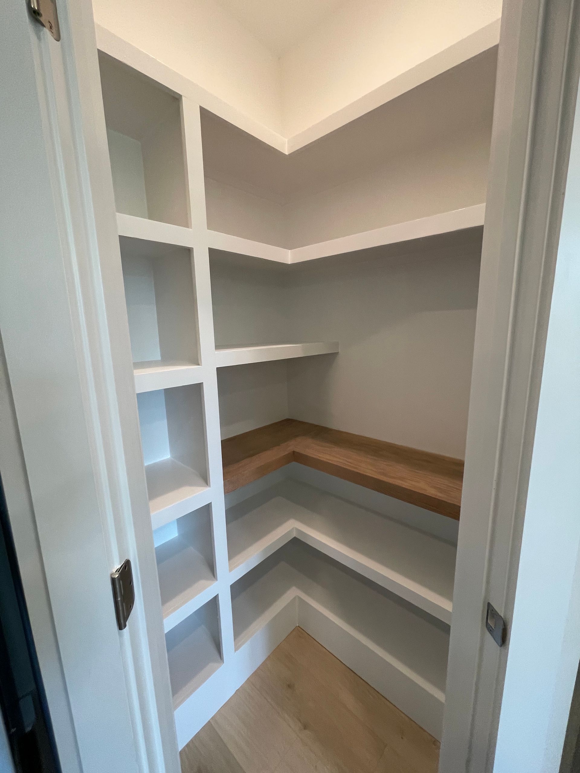 A pantry with lots of shelves and wooden shelves in a house.