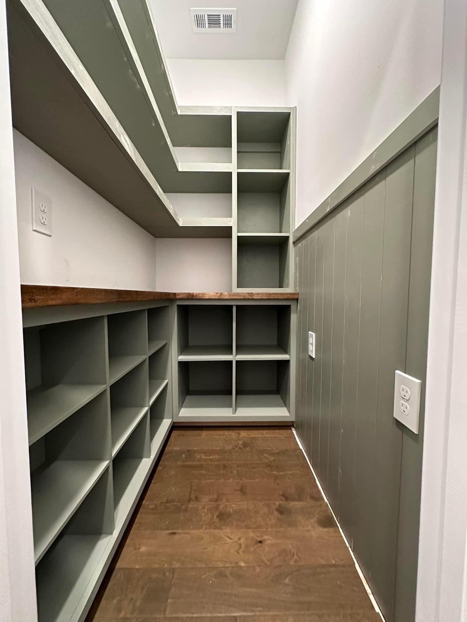 A walk in pantry with lots of shelves and wooden floors.