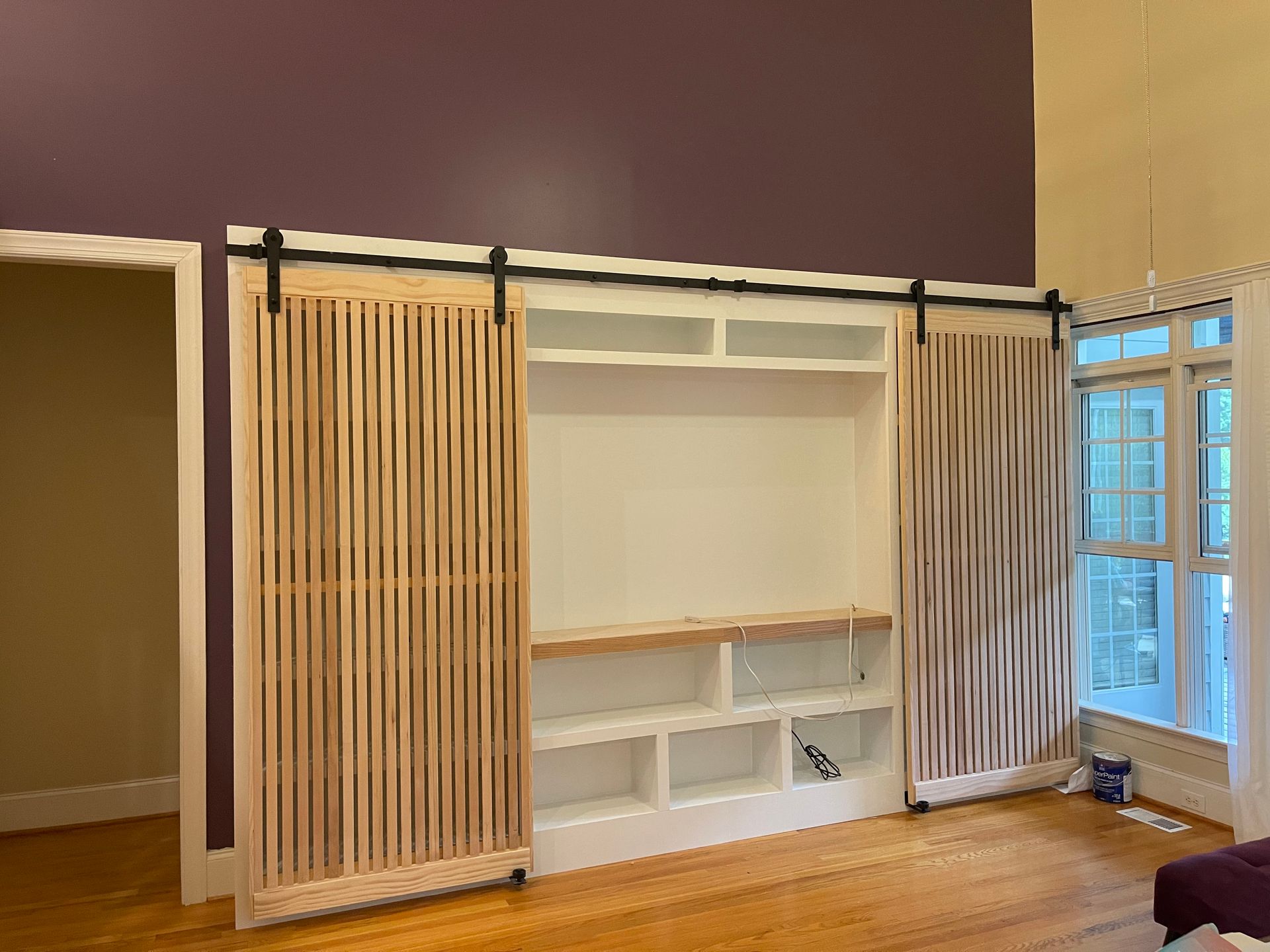 A living room with a purple wall and sliding barn doors.
