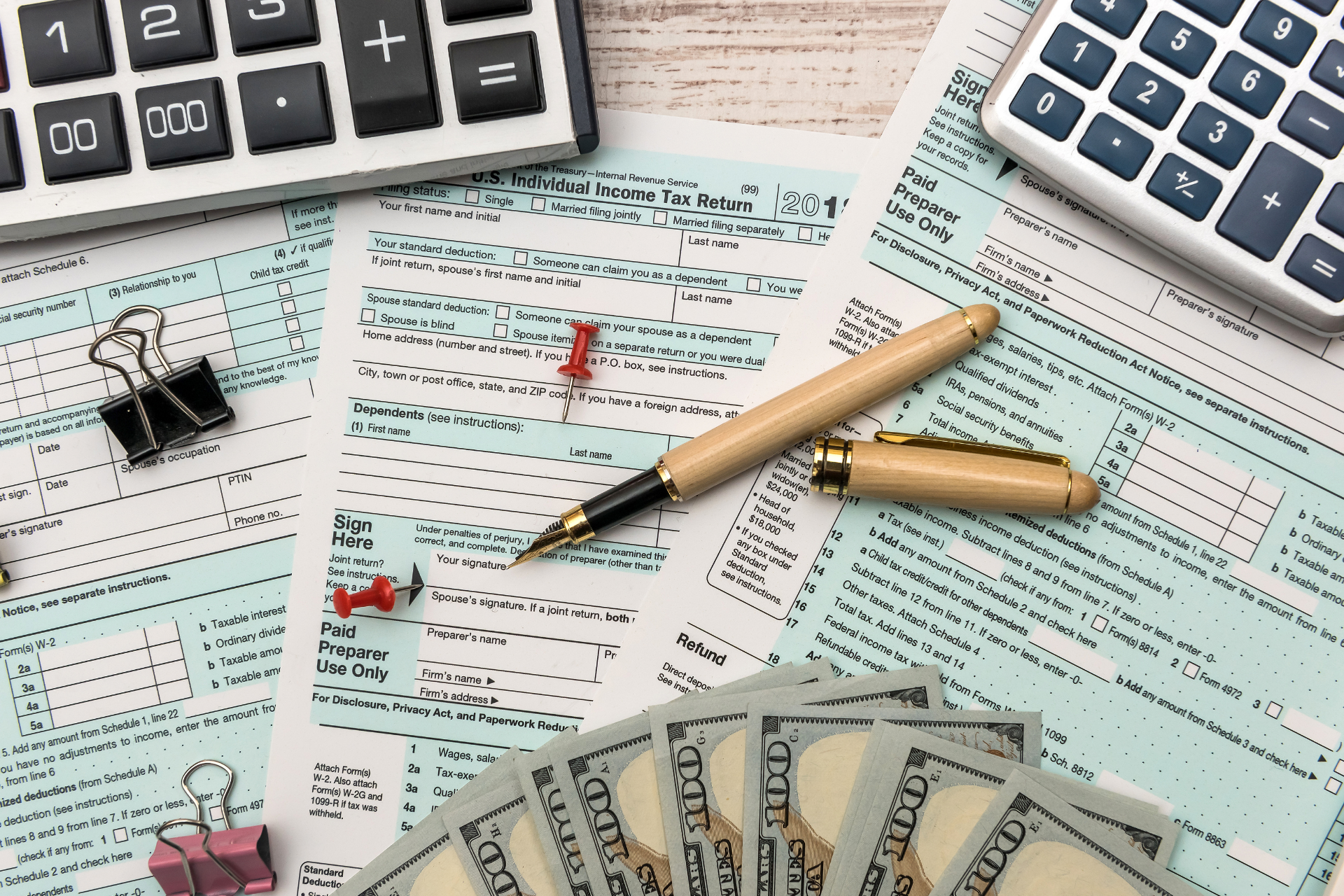 Calculator, pen, tax forms, and cash on a desk for financial accounting work