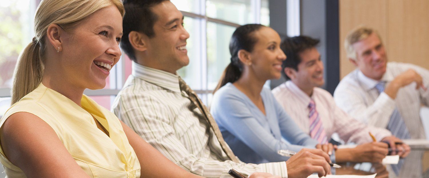 A group of people are sitting at a table in a conference room.