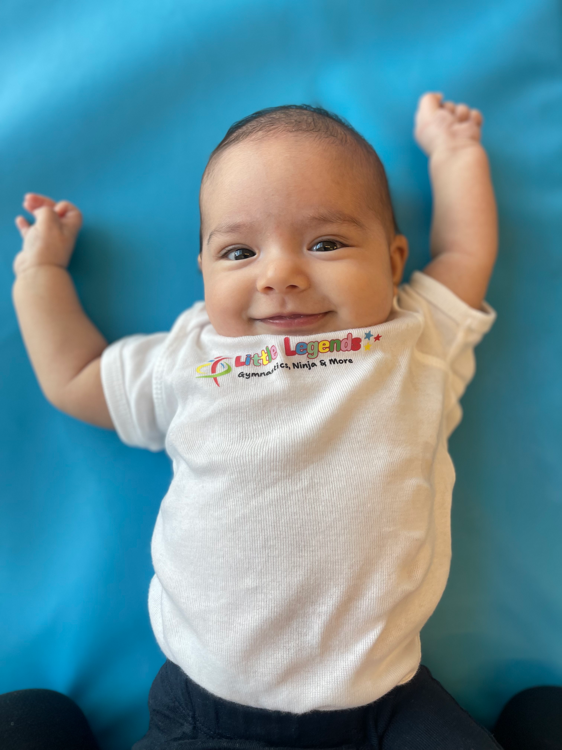 Woman lying on floor, holding up a smiling child in a yellow shirt.