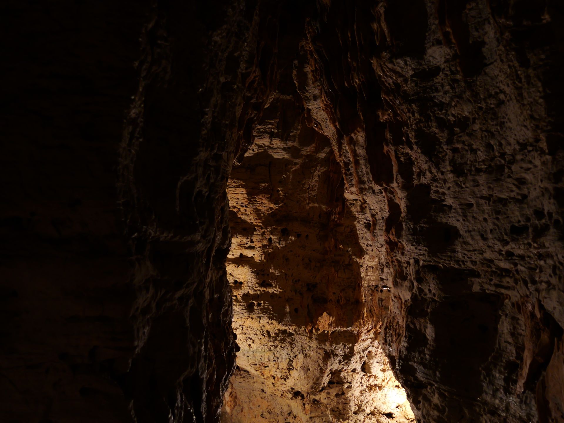 A dark cave with a light shining through the ceiling.