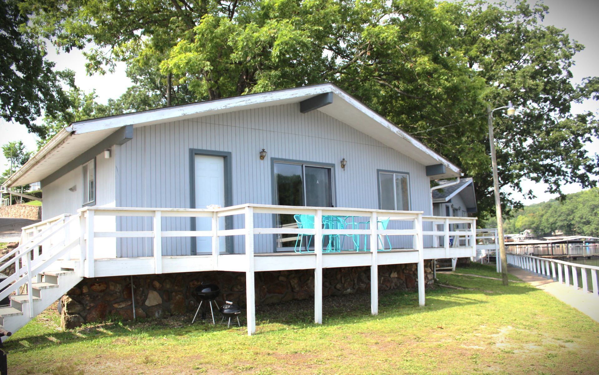 A small white house with a large deck and stairs.