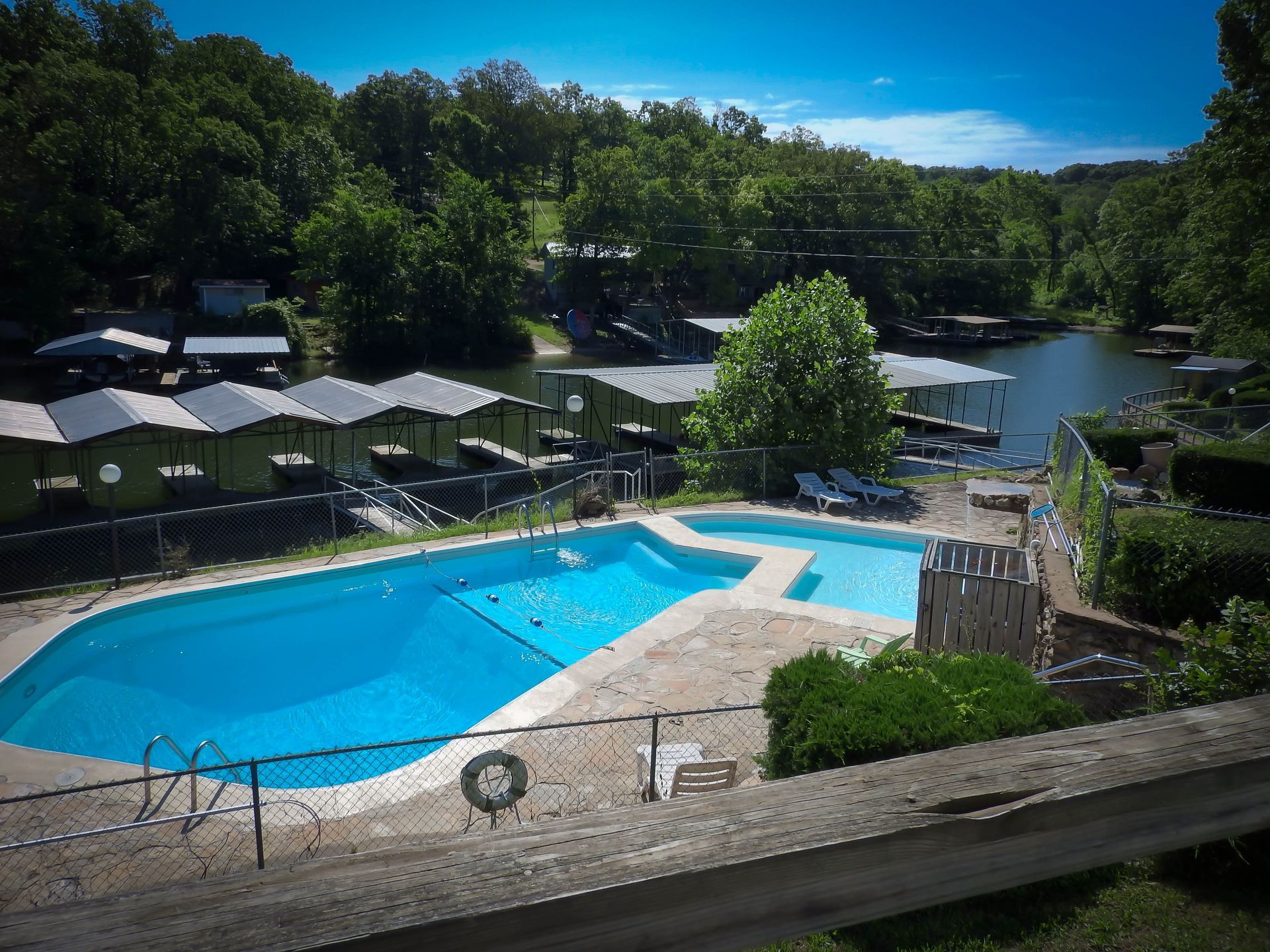 A large swimming pool surrounded by trees and a lake