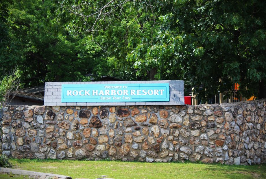 A stone wall with a sign that says rock harbor resort