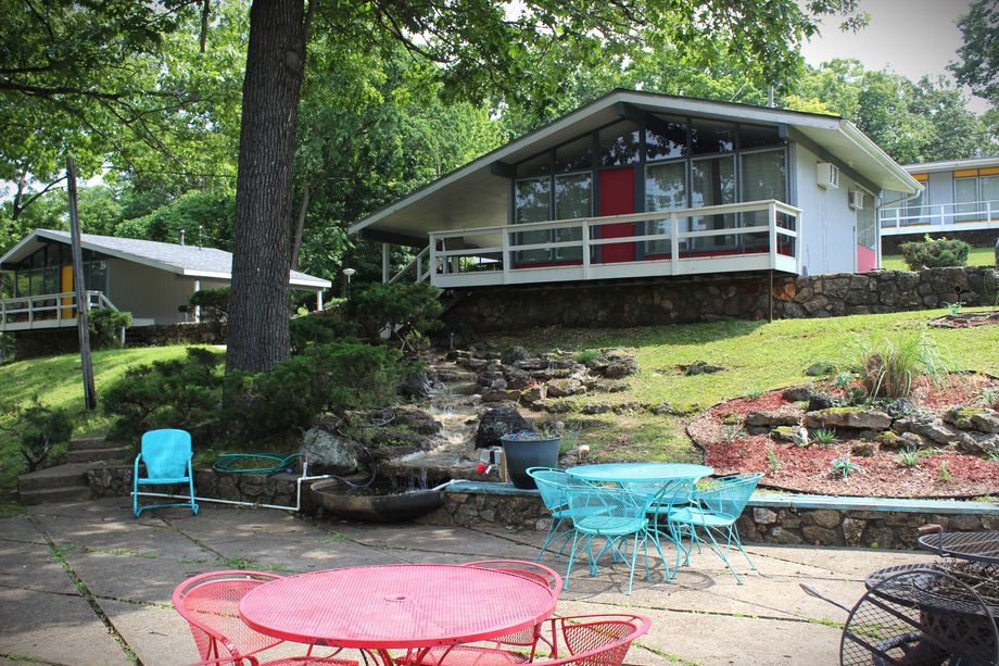 A house with a red door and a red table and chairs in front of it