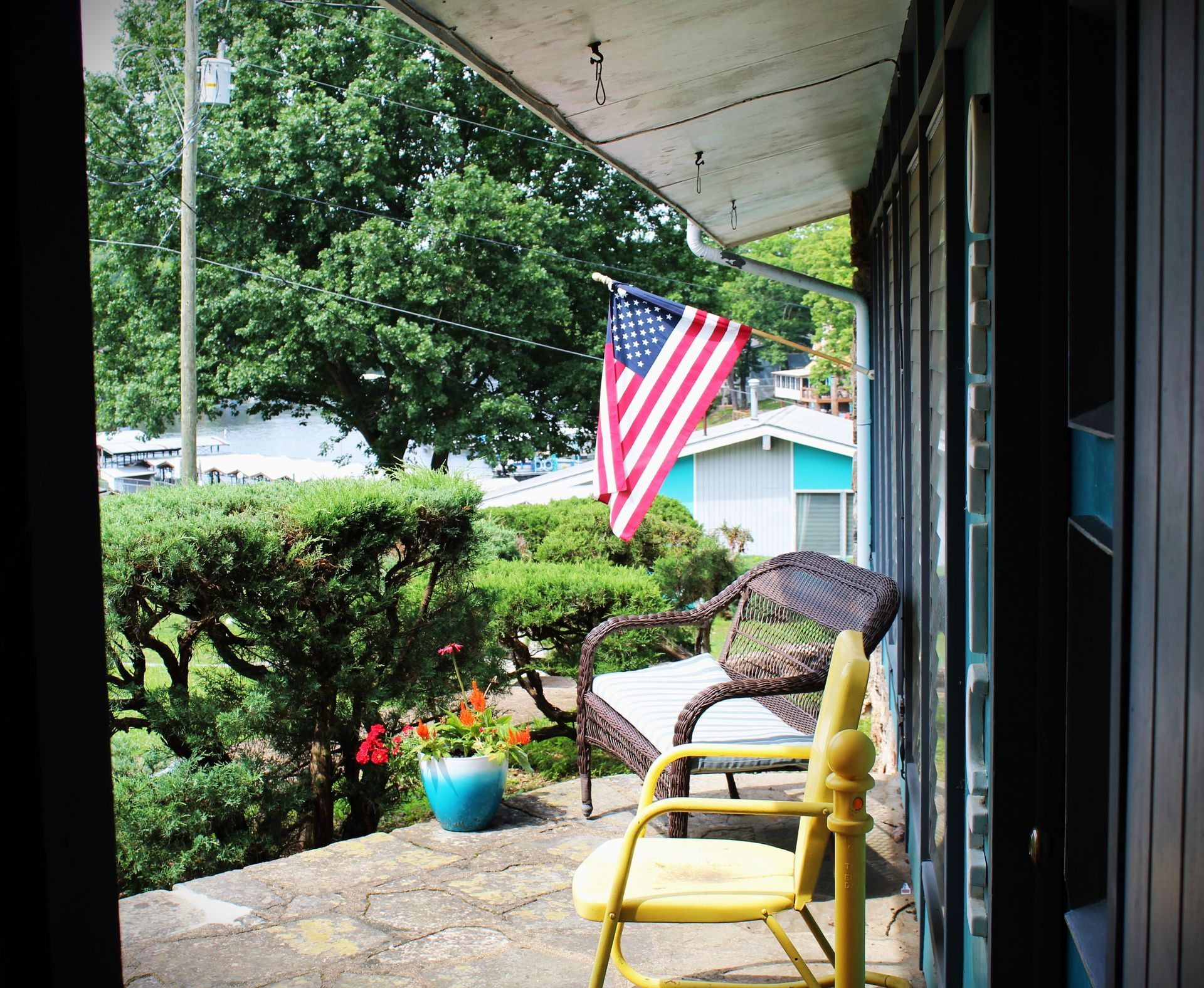 A porch with a yellow chair and an american flag