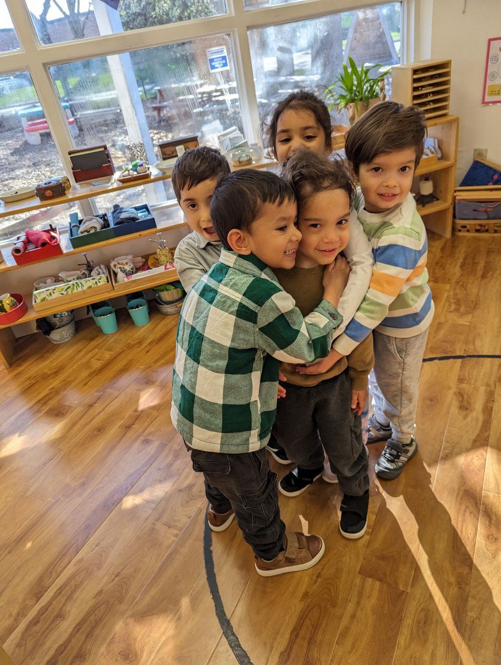 A group of children are hugging each other in a room.