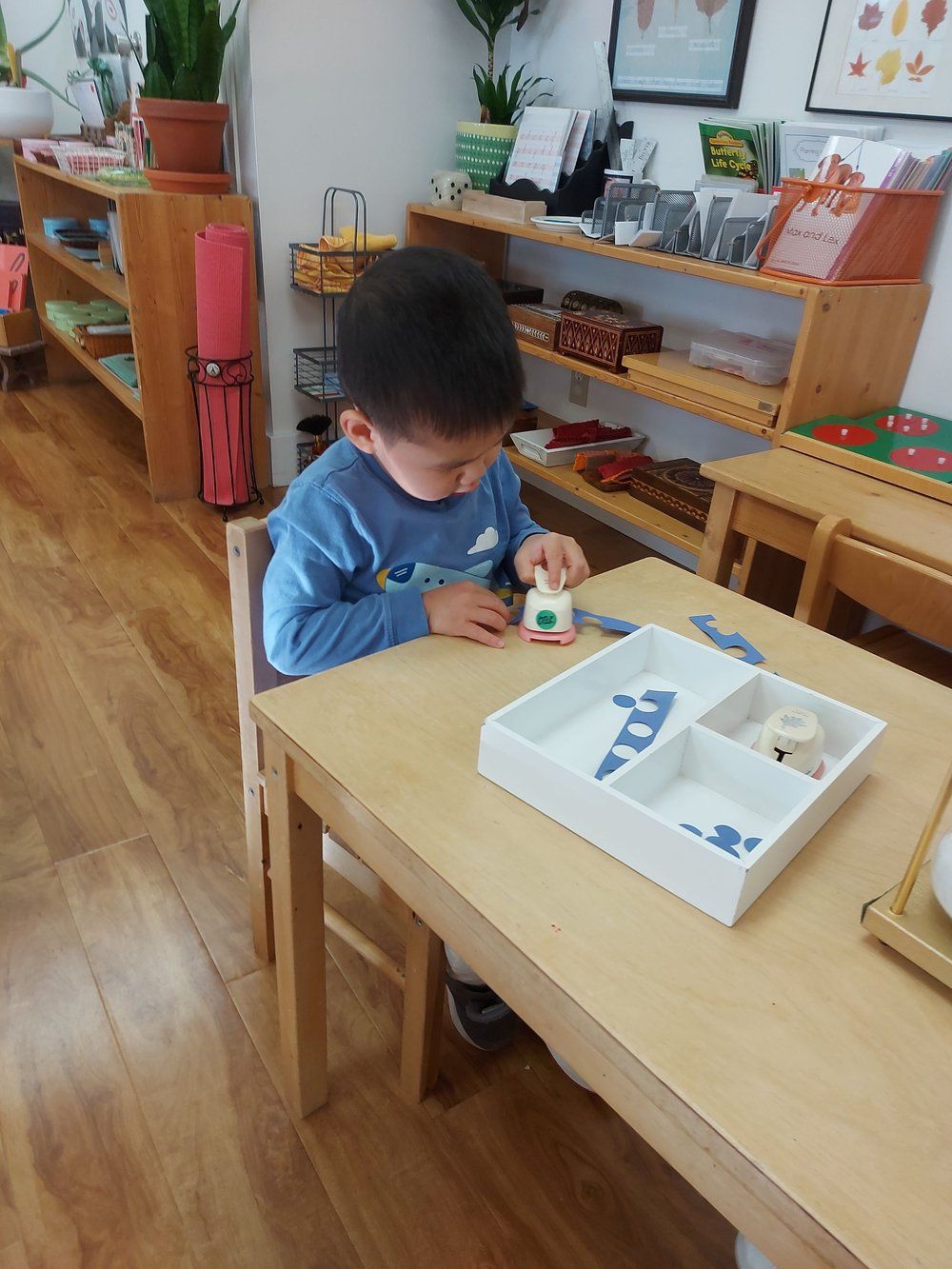 A young boy is sitting at a table playing with toys.