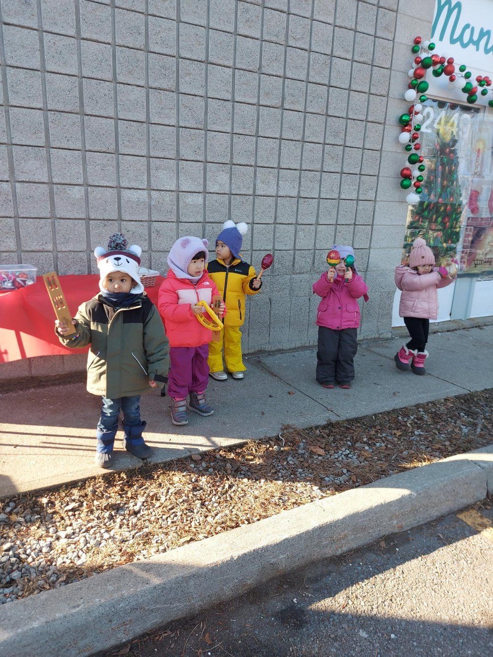 A group of children are standing on the sidewalk in front of a building.
