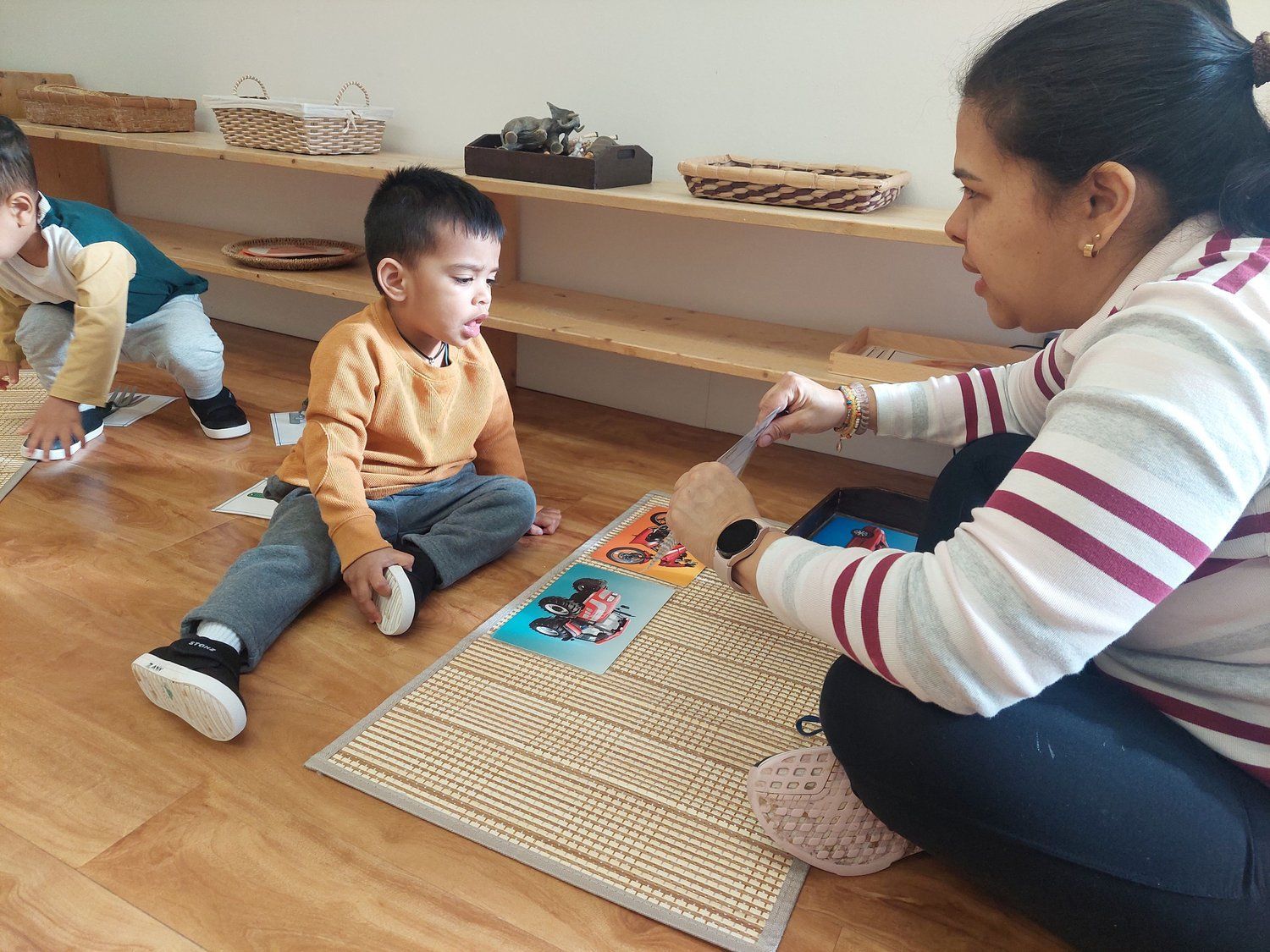 A woman is sitting on the floor playing with two children.