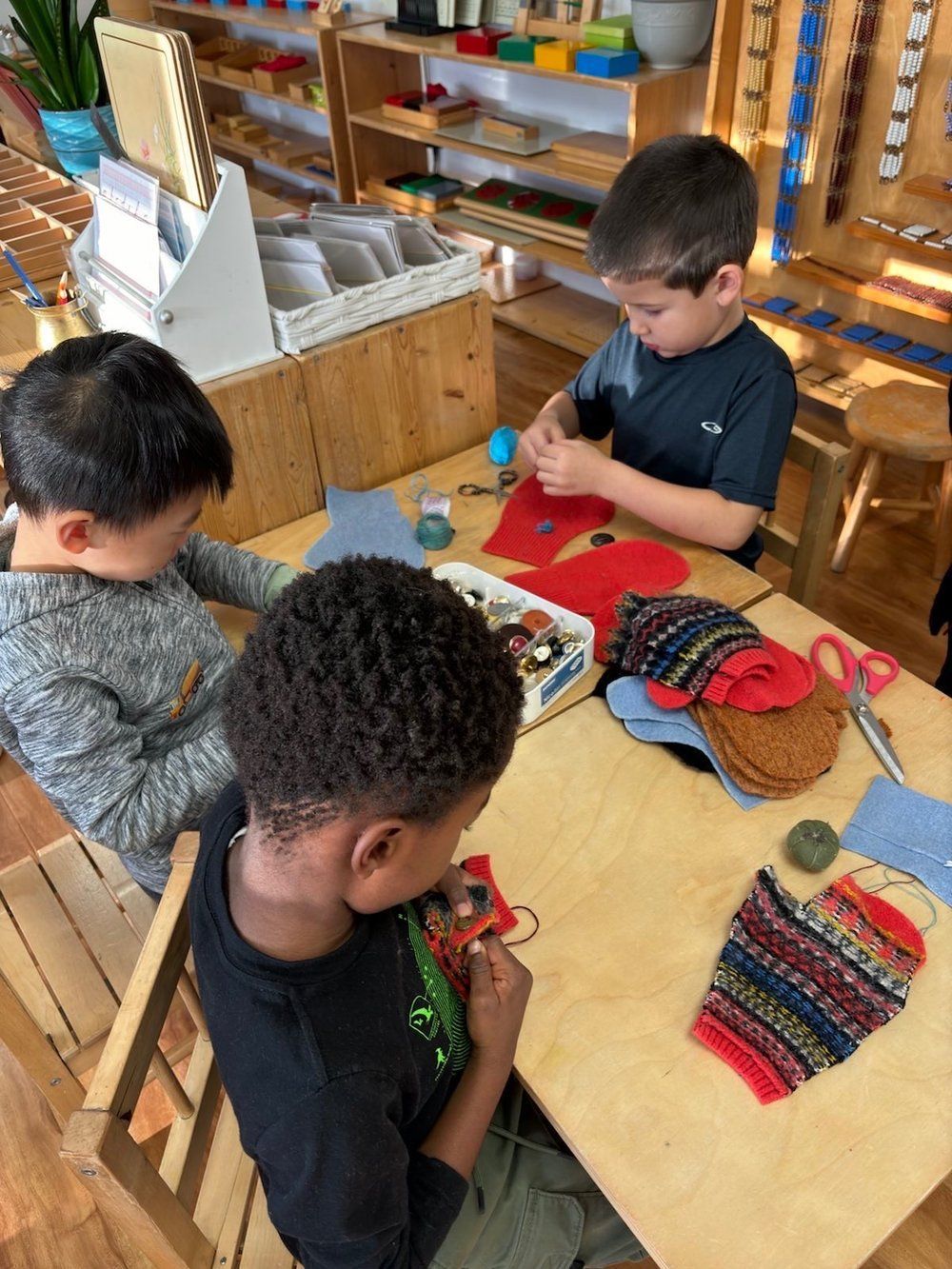 Three young boys are sitting at a table making crafts.