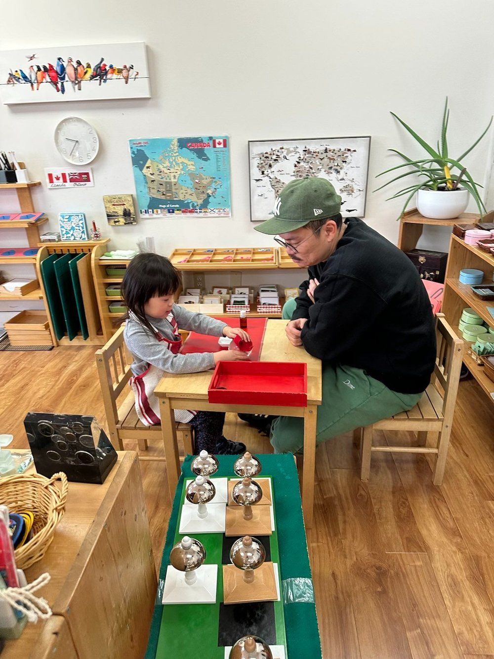 A man and a little girl are sitting at a table in a classroom.