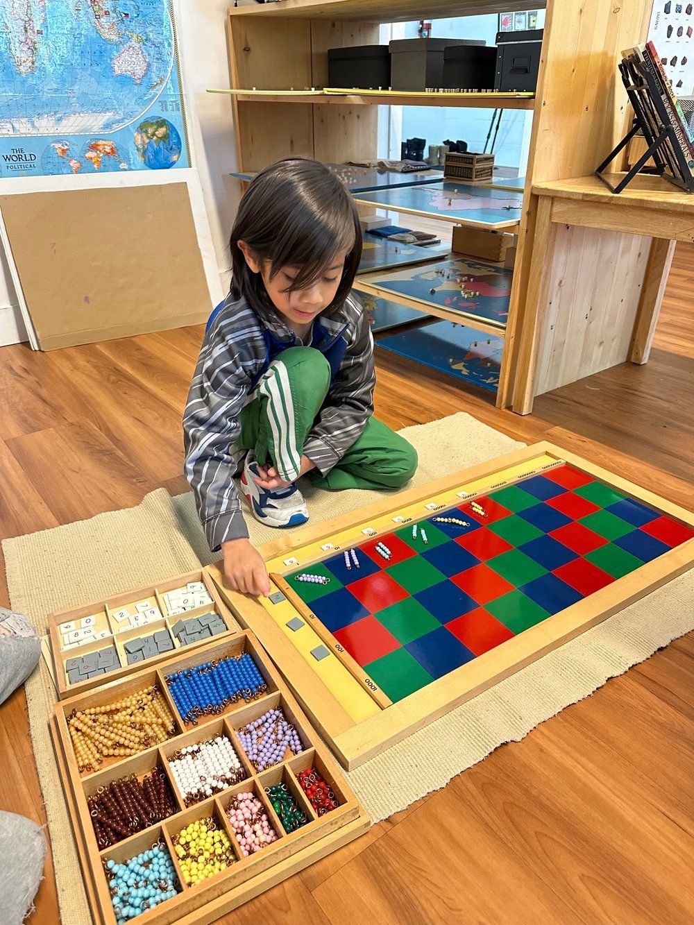 A young boy is sitting on the floor playing with a board game.