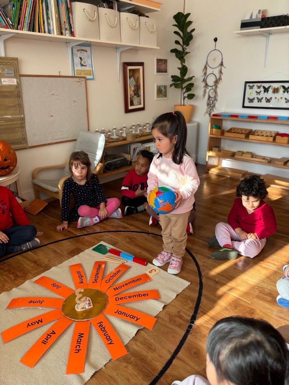 A little girl is standing in a circle holding a ball.