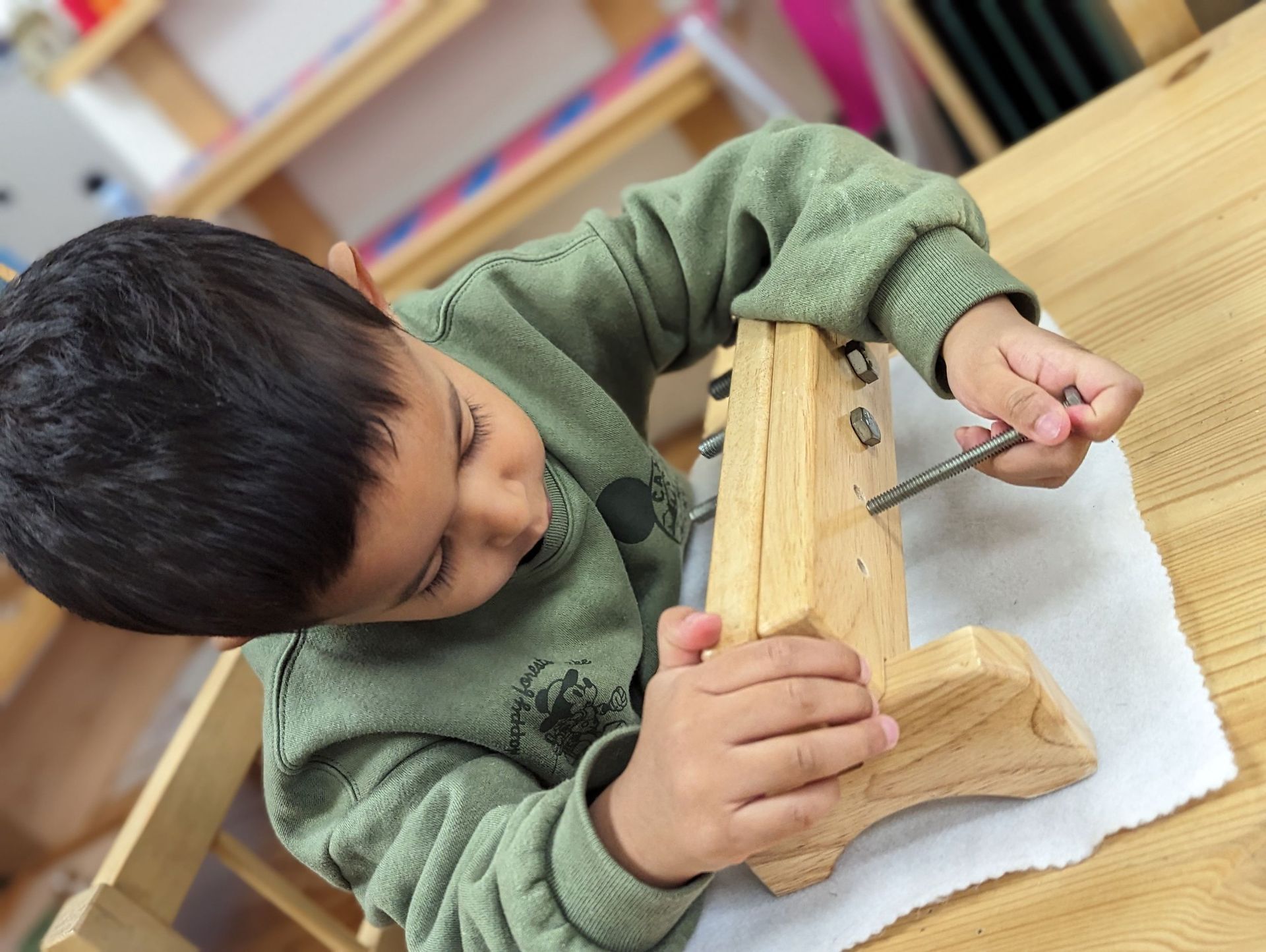 A young boy is using a screwdriver to fix a piece of wood.