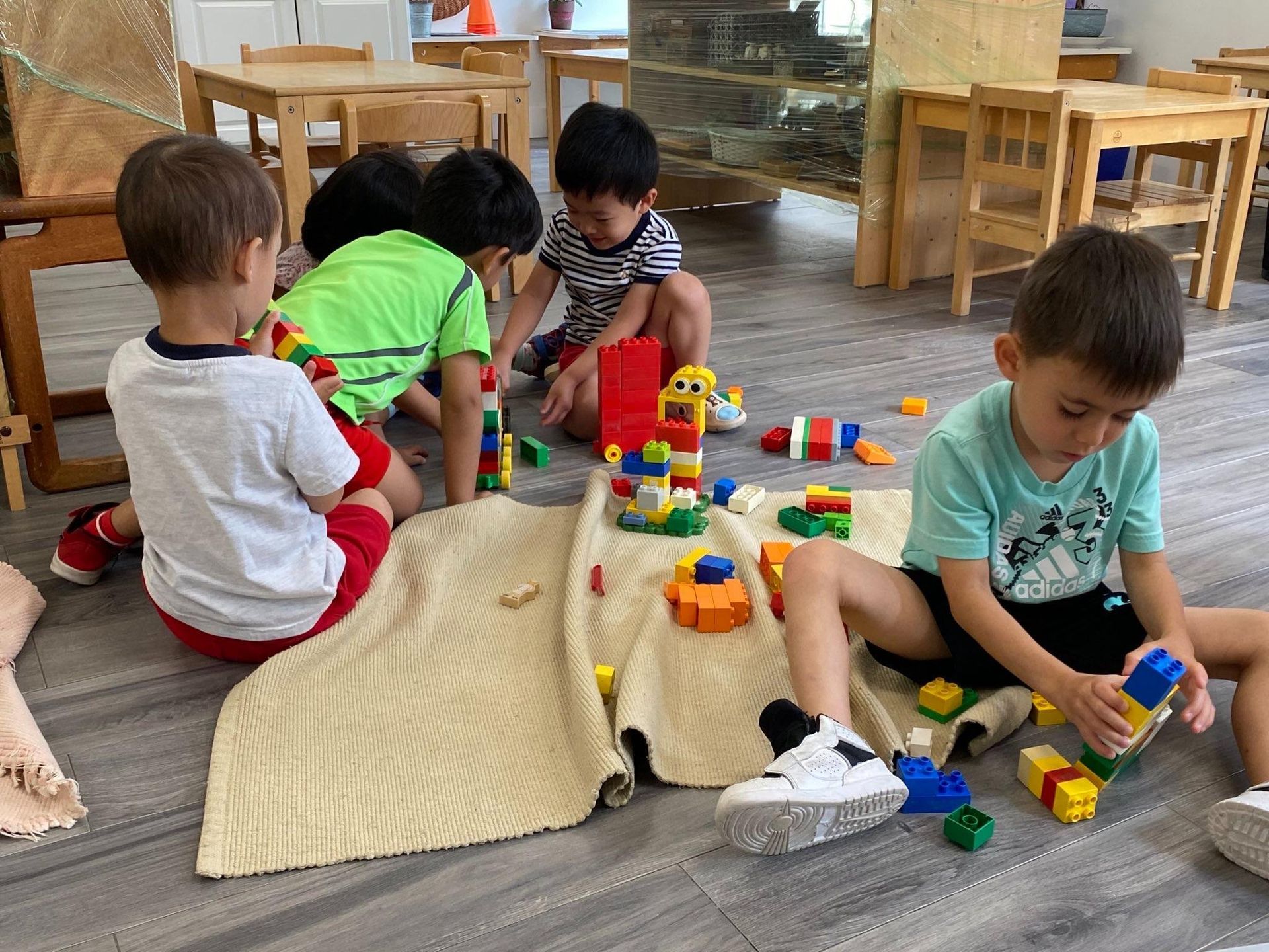 A group of children are sitting on the floor playing with lego blocks.