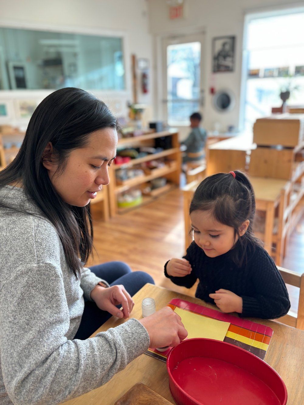 A woman is sitting at a table with a little girl.