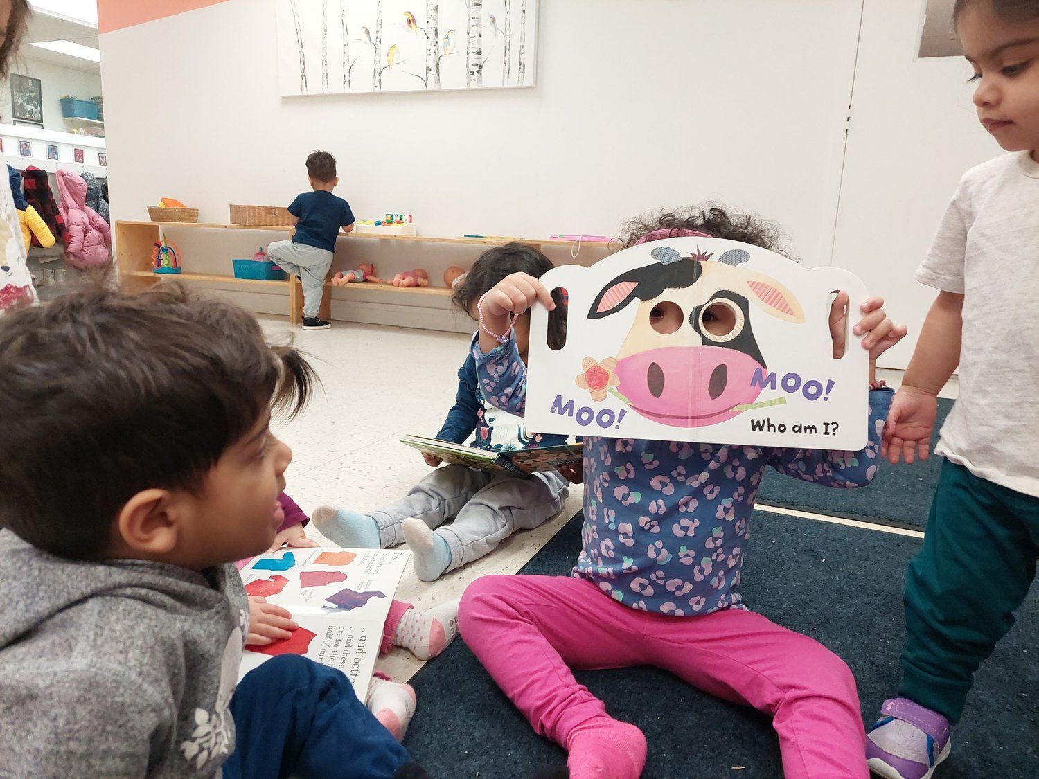 A little girl is holding a picture of a cow in front of her face.