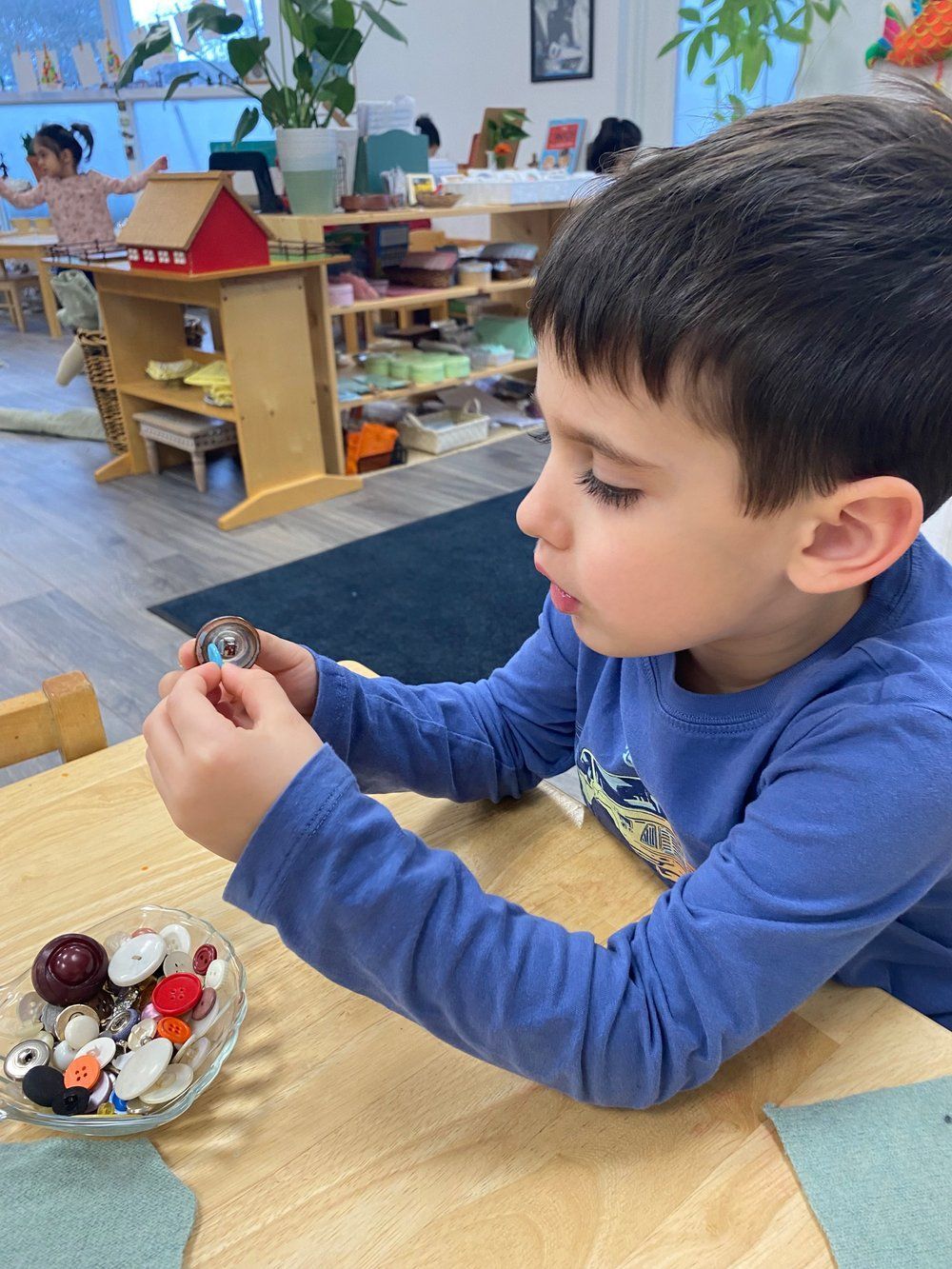 A young boy is sitting at a table playing with buttons.