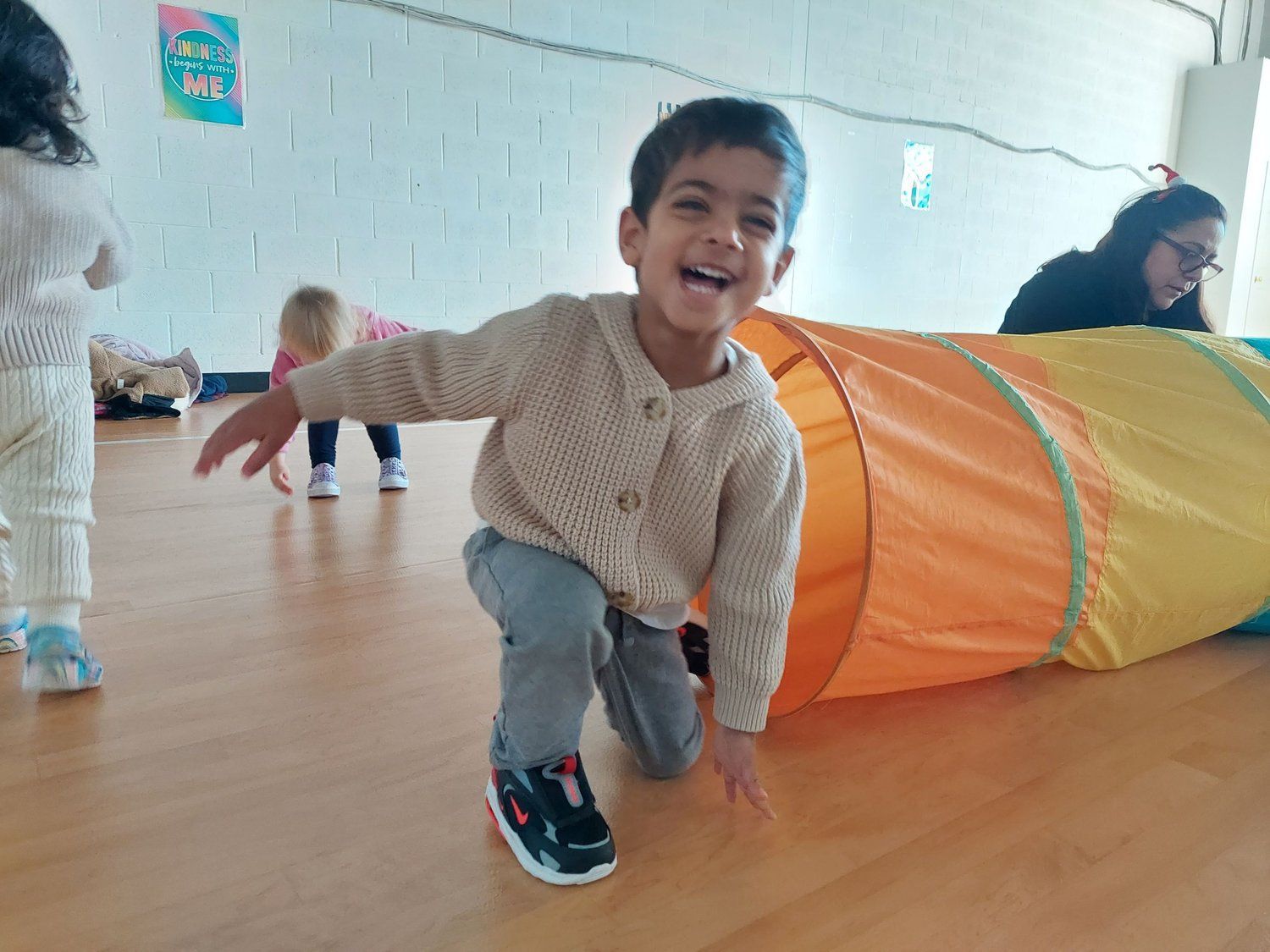 A little boy is crawling through a tunnel on the floor.