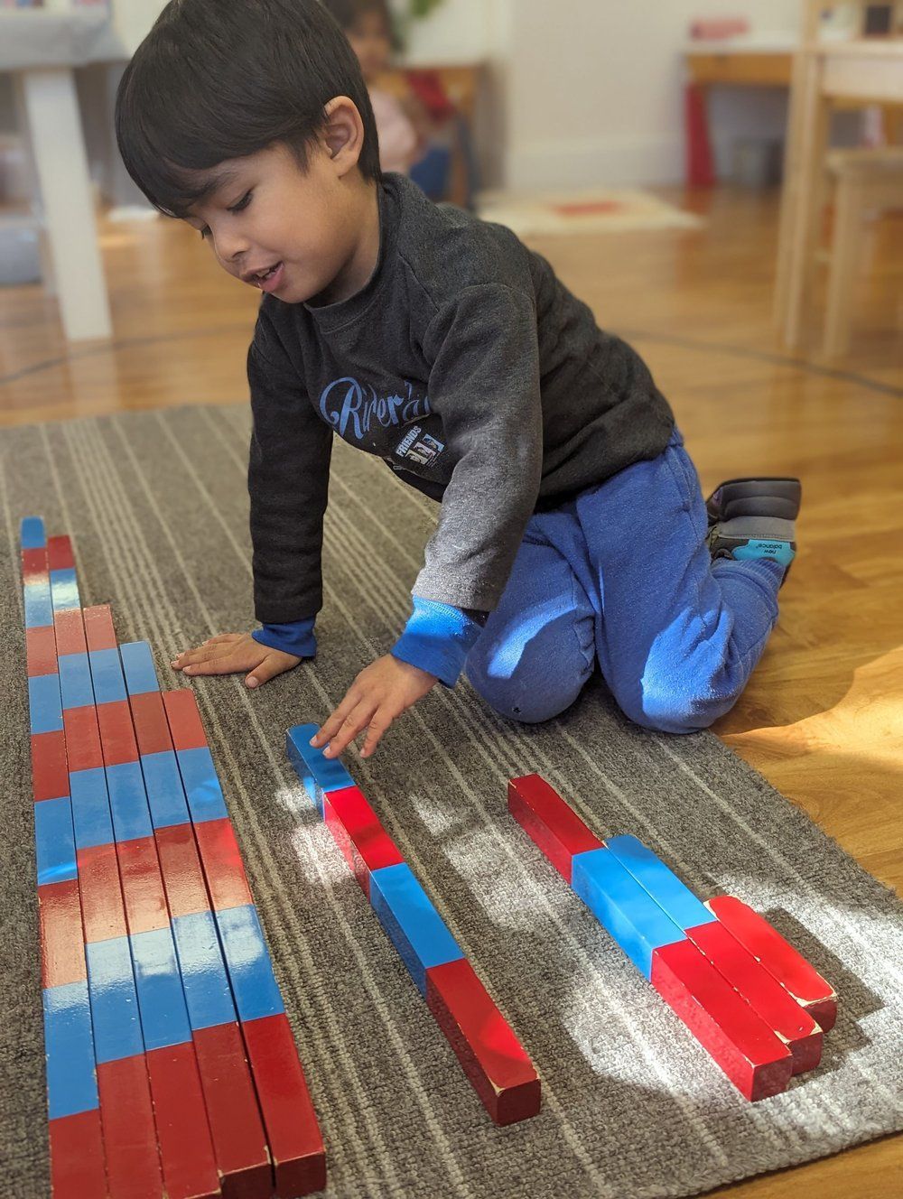 A young boy is playing with wooden blocks on the floor.