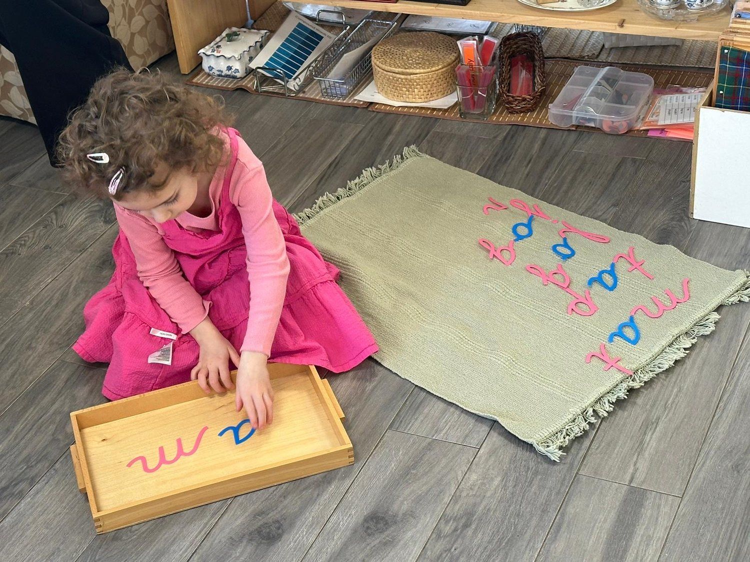 A little girl is sitting on the floor playing with a wooden tray.