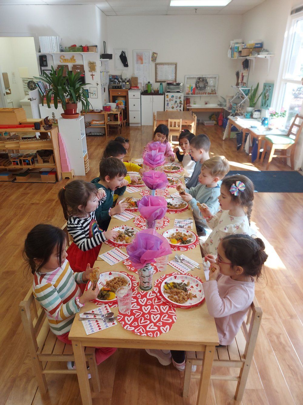 A group of children are sitting at a table eating food.