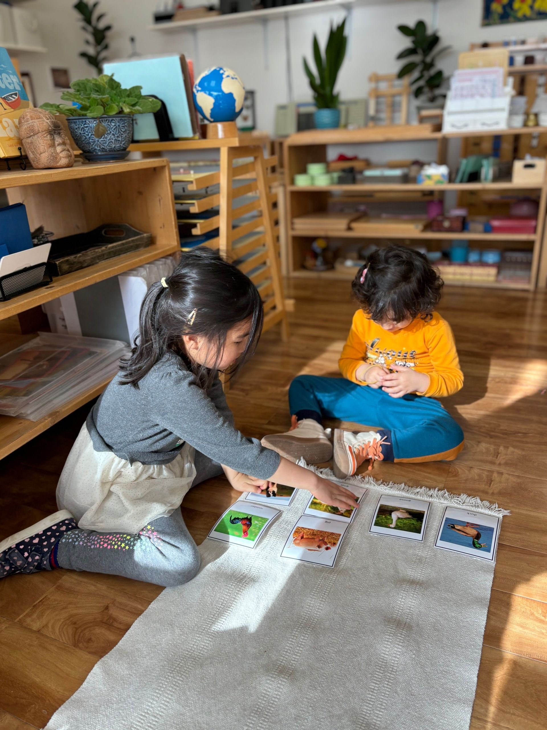 Two young girls are sitting on the floor playing with cards.