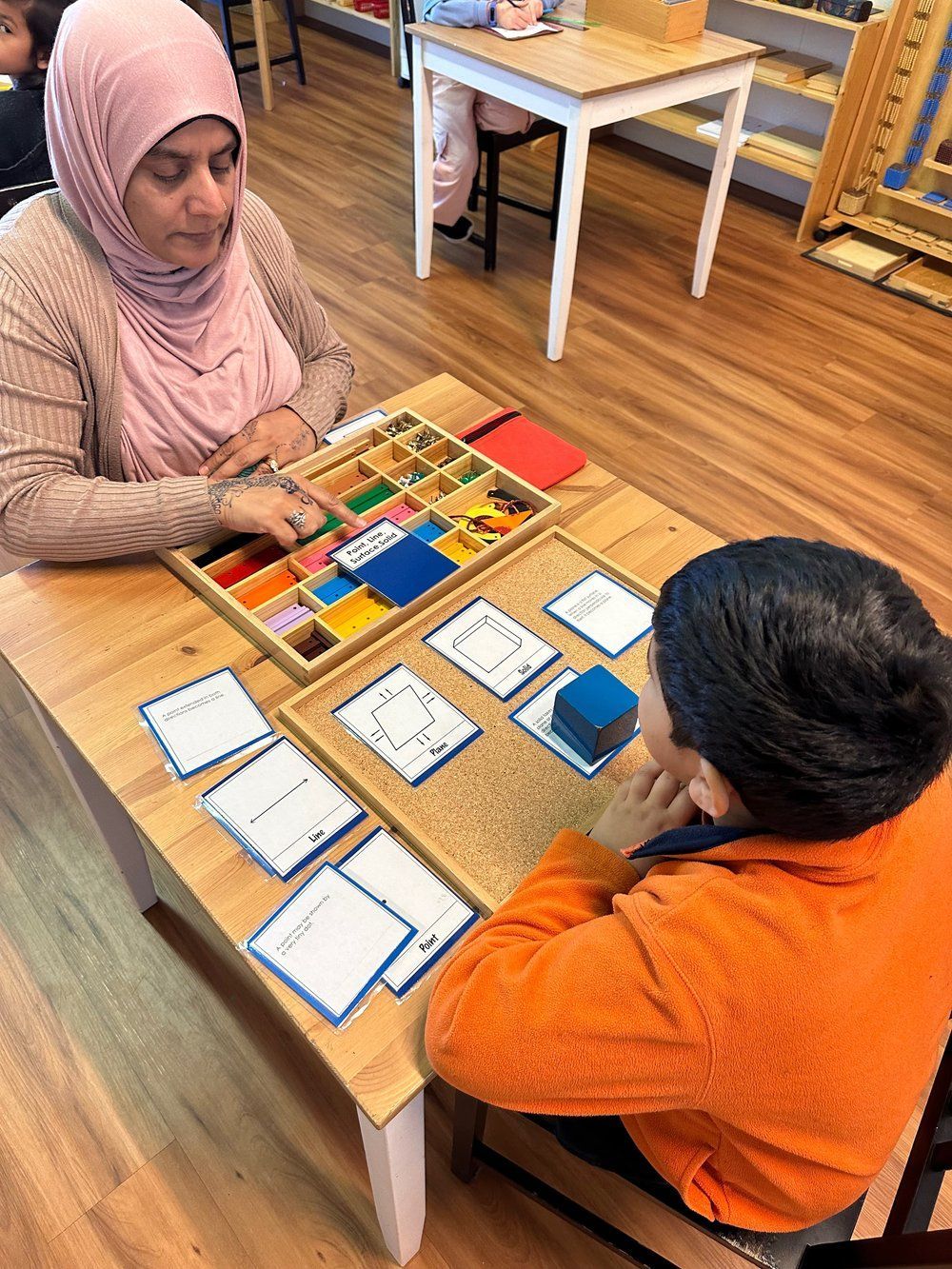 A woman and a boy are sitting at a table playing a game.