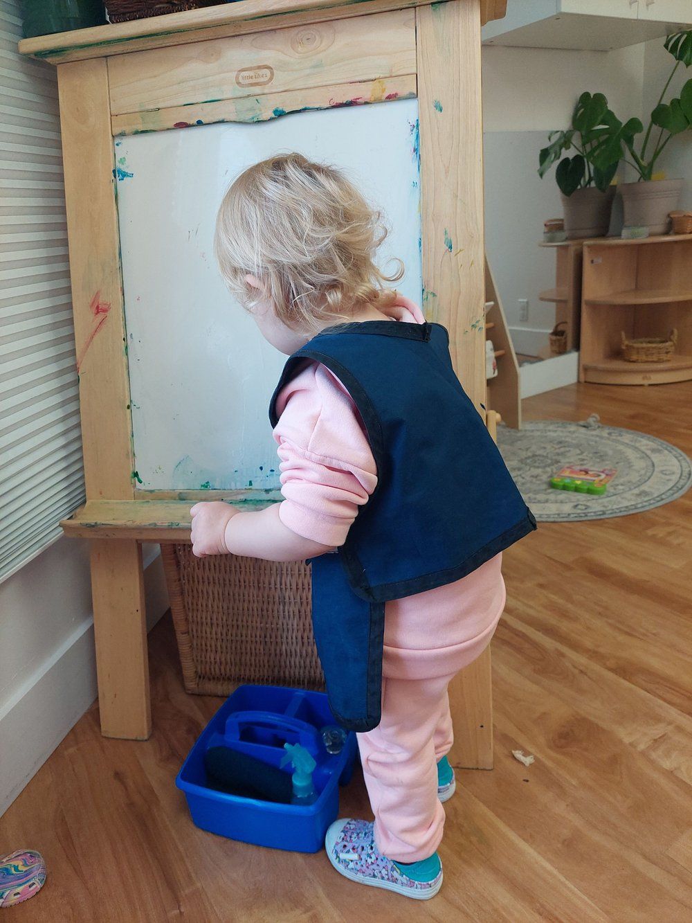A little girl is standing in front of a white board.