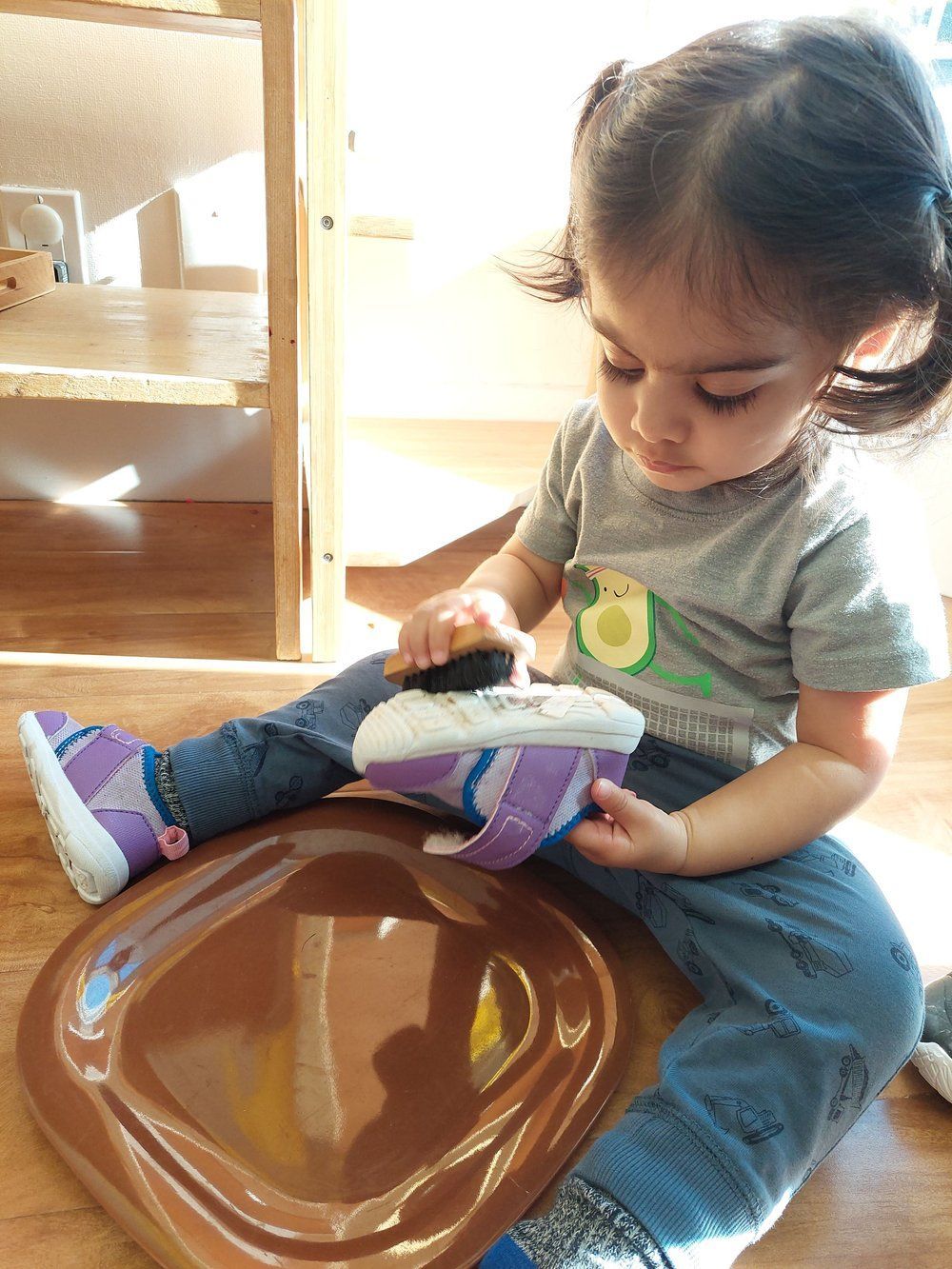 A little girl is sitting on the floor playing with a toy.