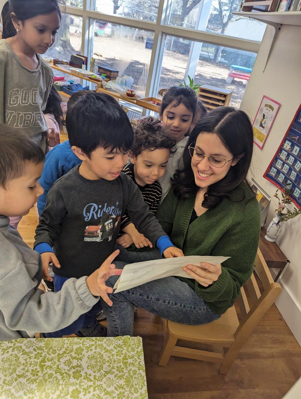 A woman is reading a book to a group of children in a classroom.