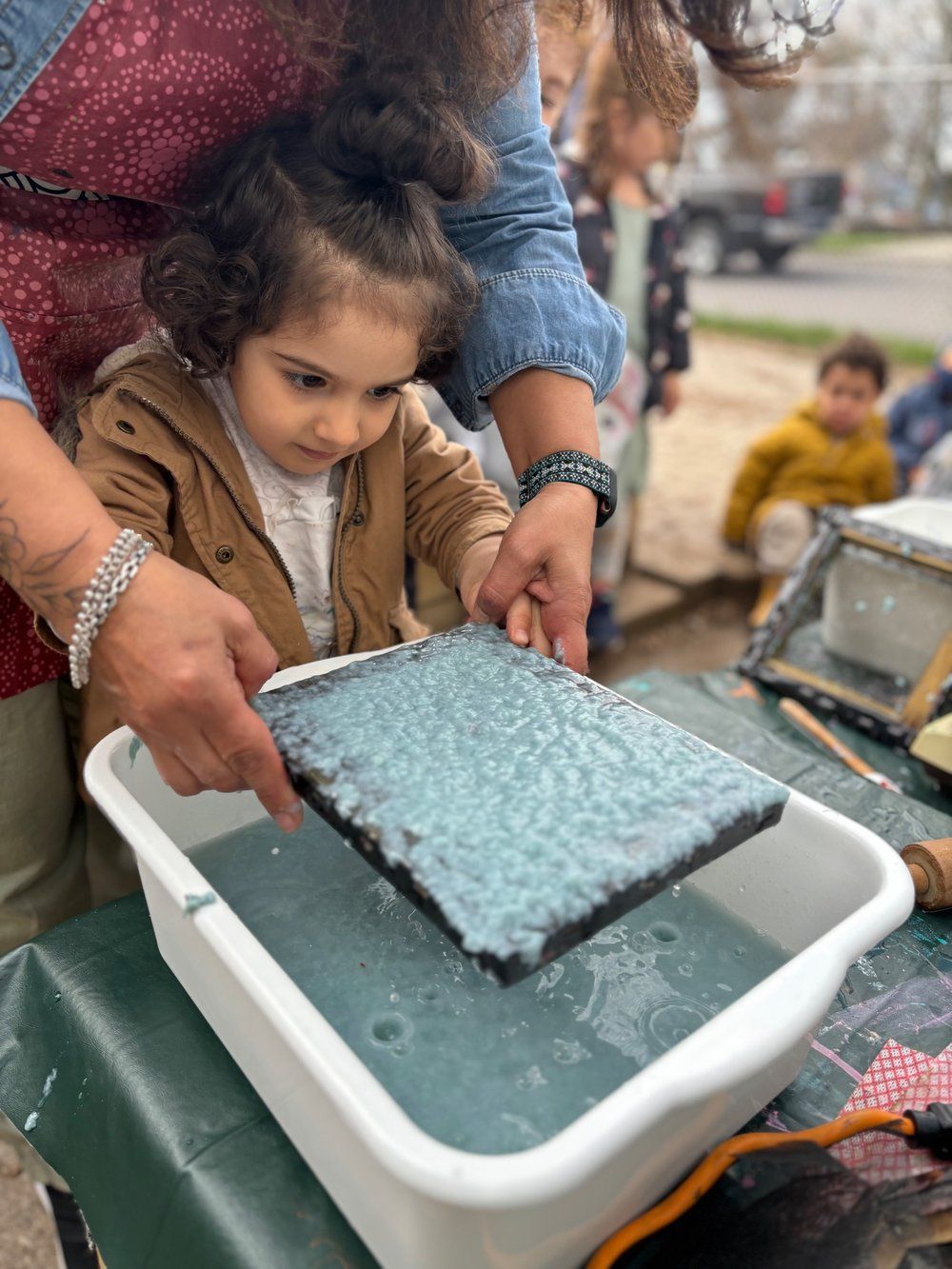 A woman is teaching a little girl how to make paper.