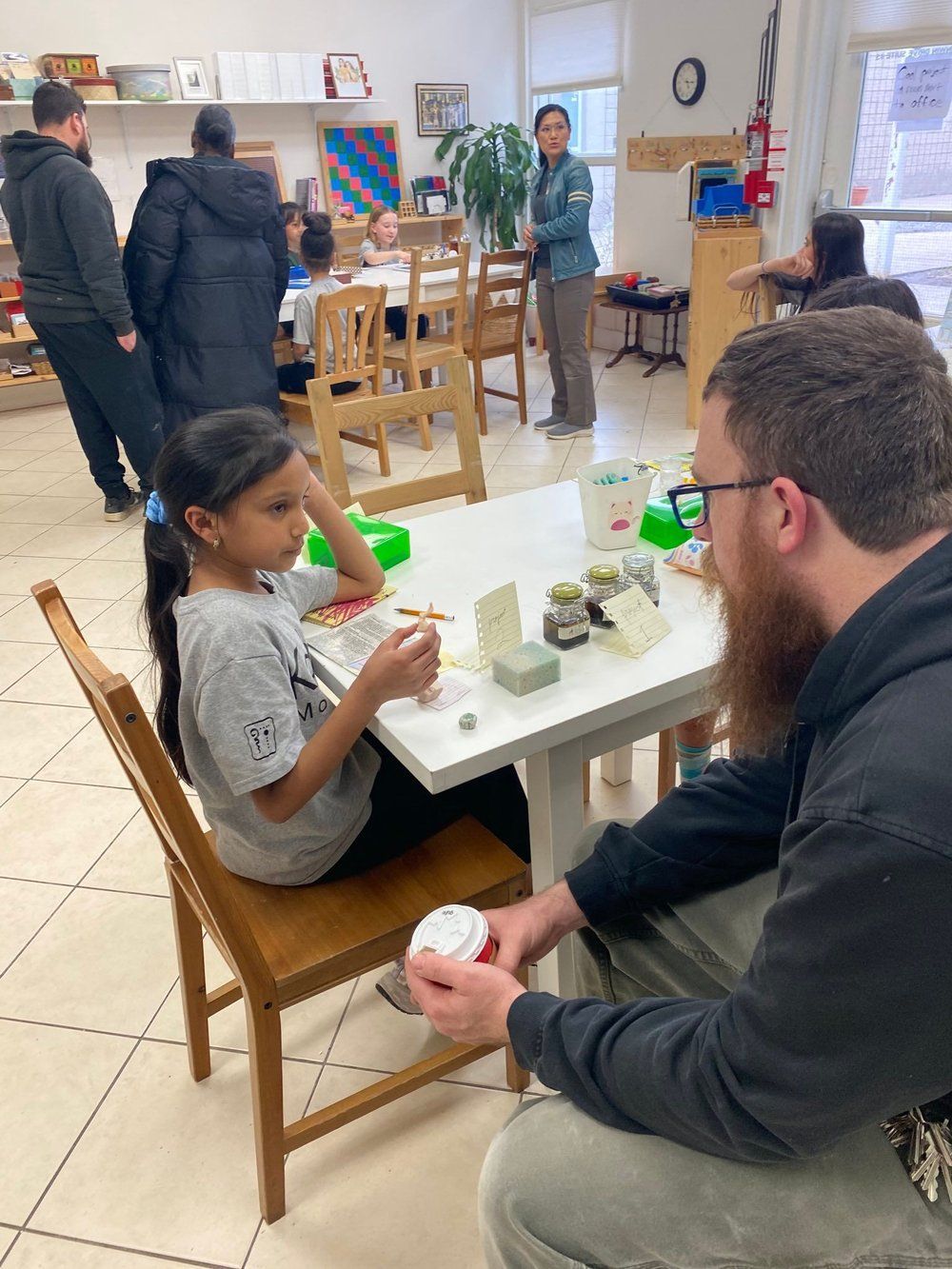 A man and a girl are sitting at a table in a room.