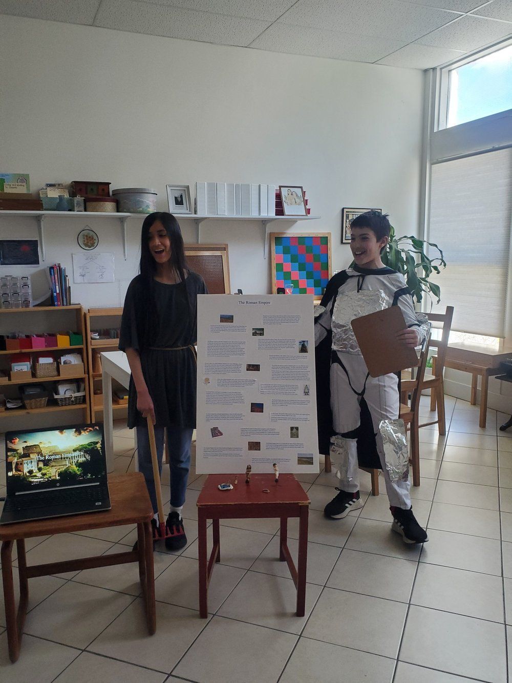 A boy and a girl are standing in a room holding a sign.
