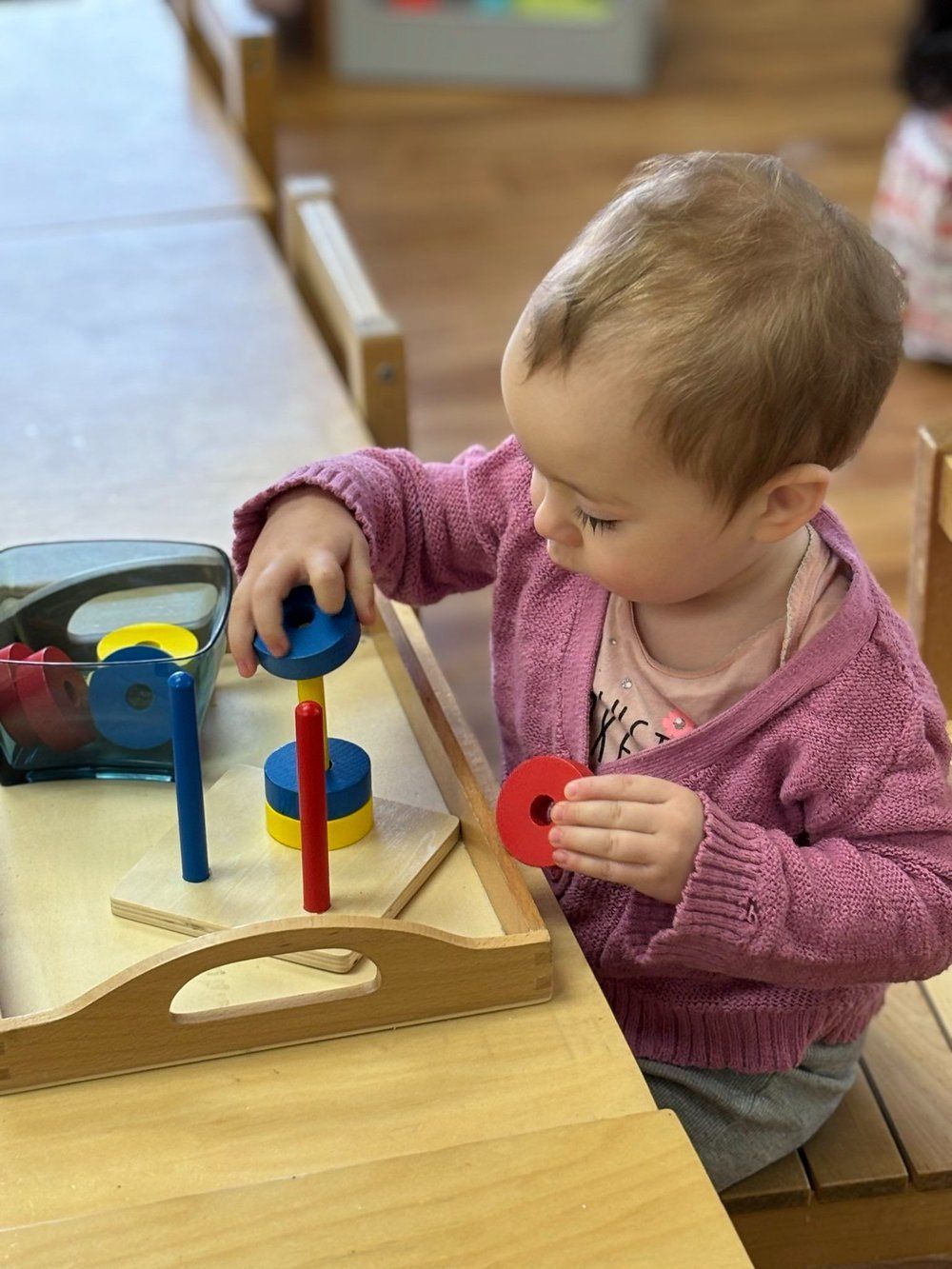 A baby is sitting at a table playing with a wooden toy.