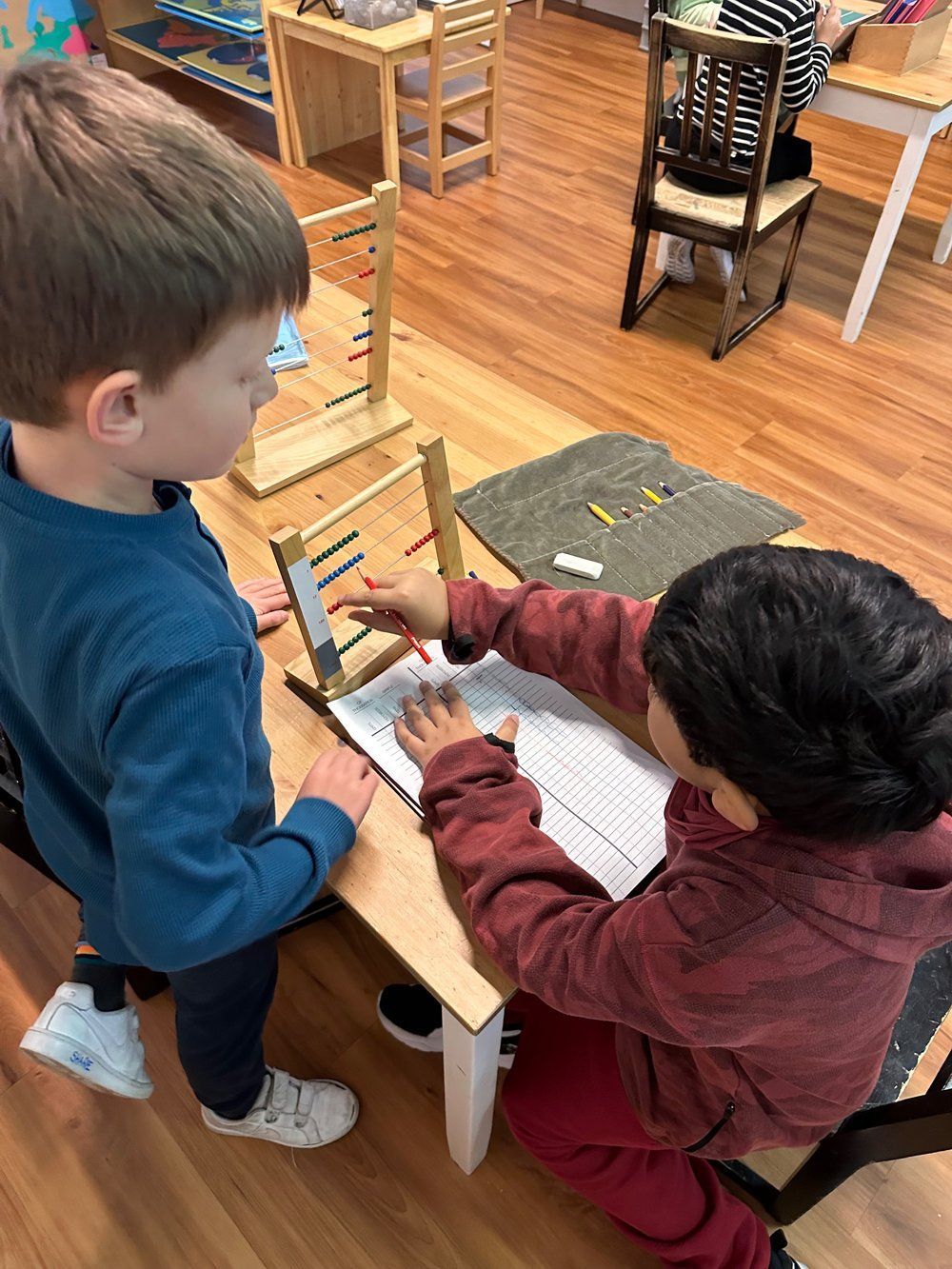 Two young boys are sitting at a table in a classroom.
