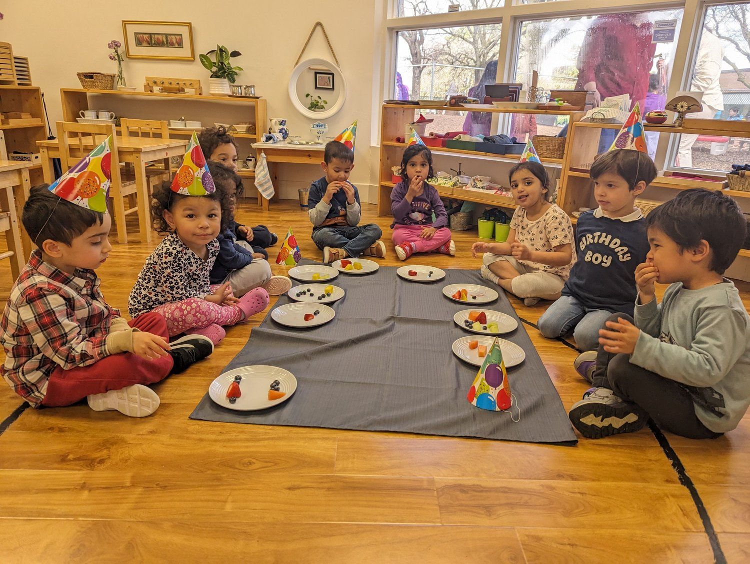 A group of children are sitting on the floor at a birthday party.