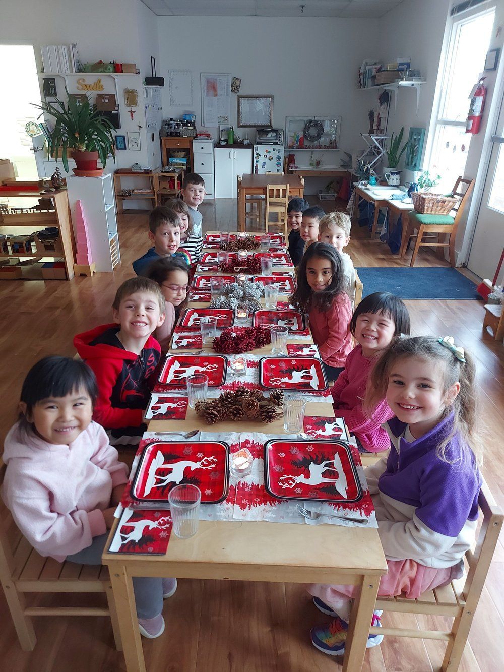 A group of children are sitting at a long table decorated for christmas.