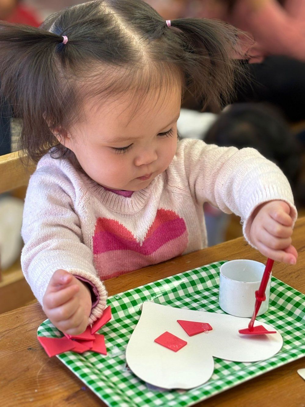 A little girl is painting a heart on a paper plate.