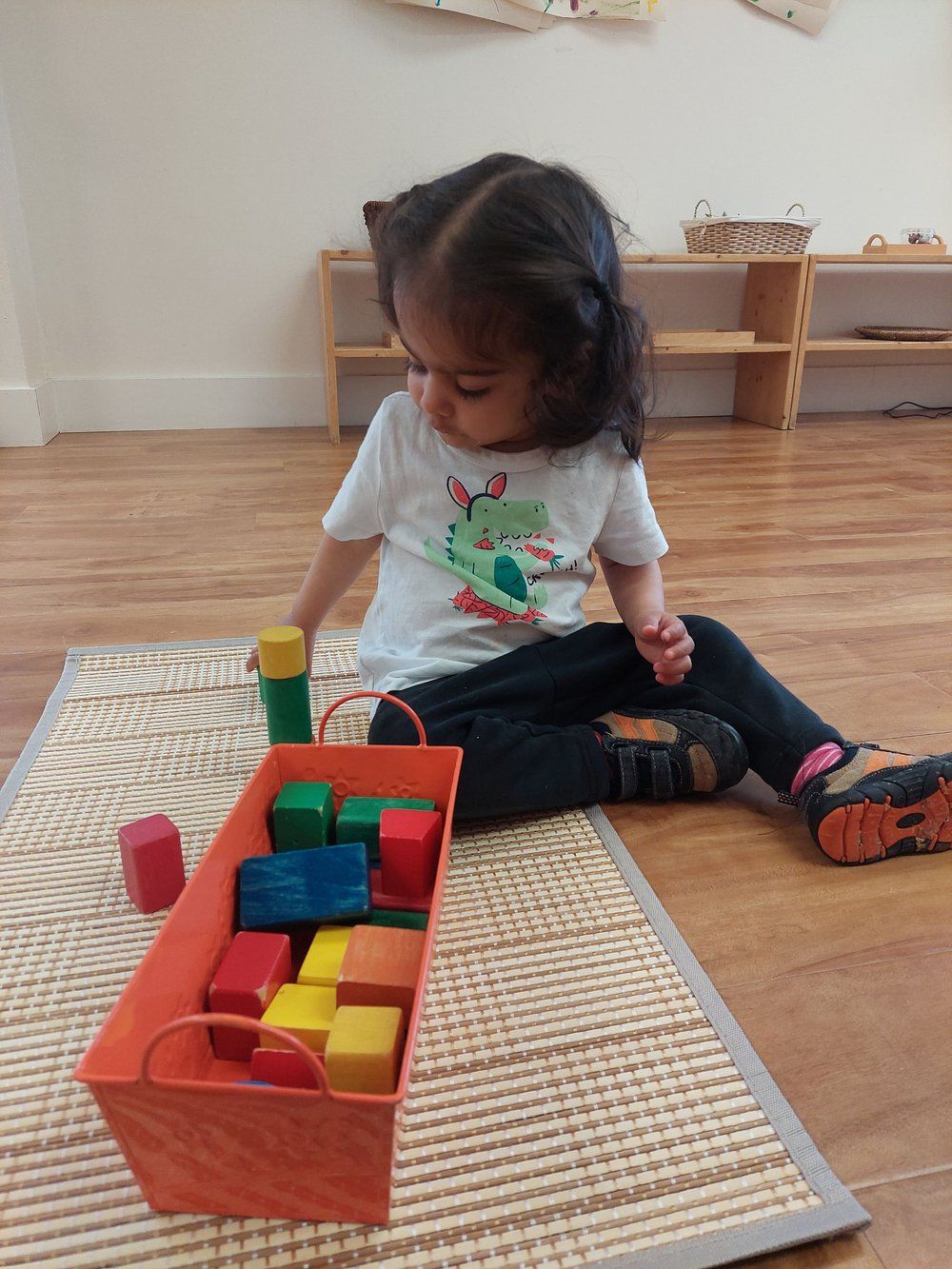 A little girl is sitting on the floor playing with blocks