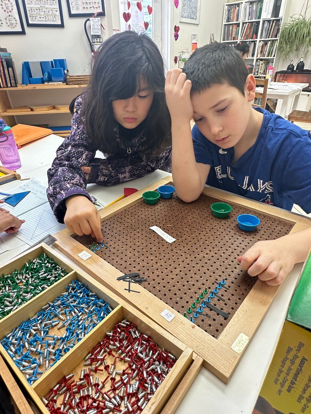 A boy and a girl are sitting at a table playing a game.