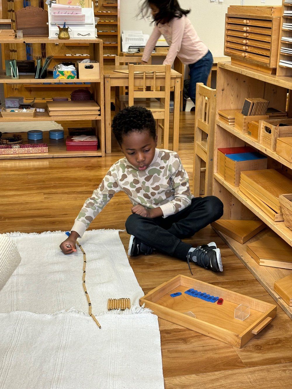 A young boy is sitting on the floor playing with a stick.