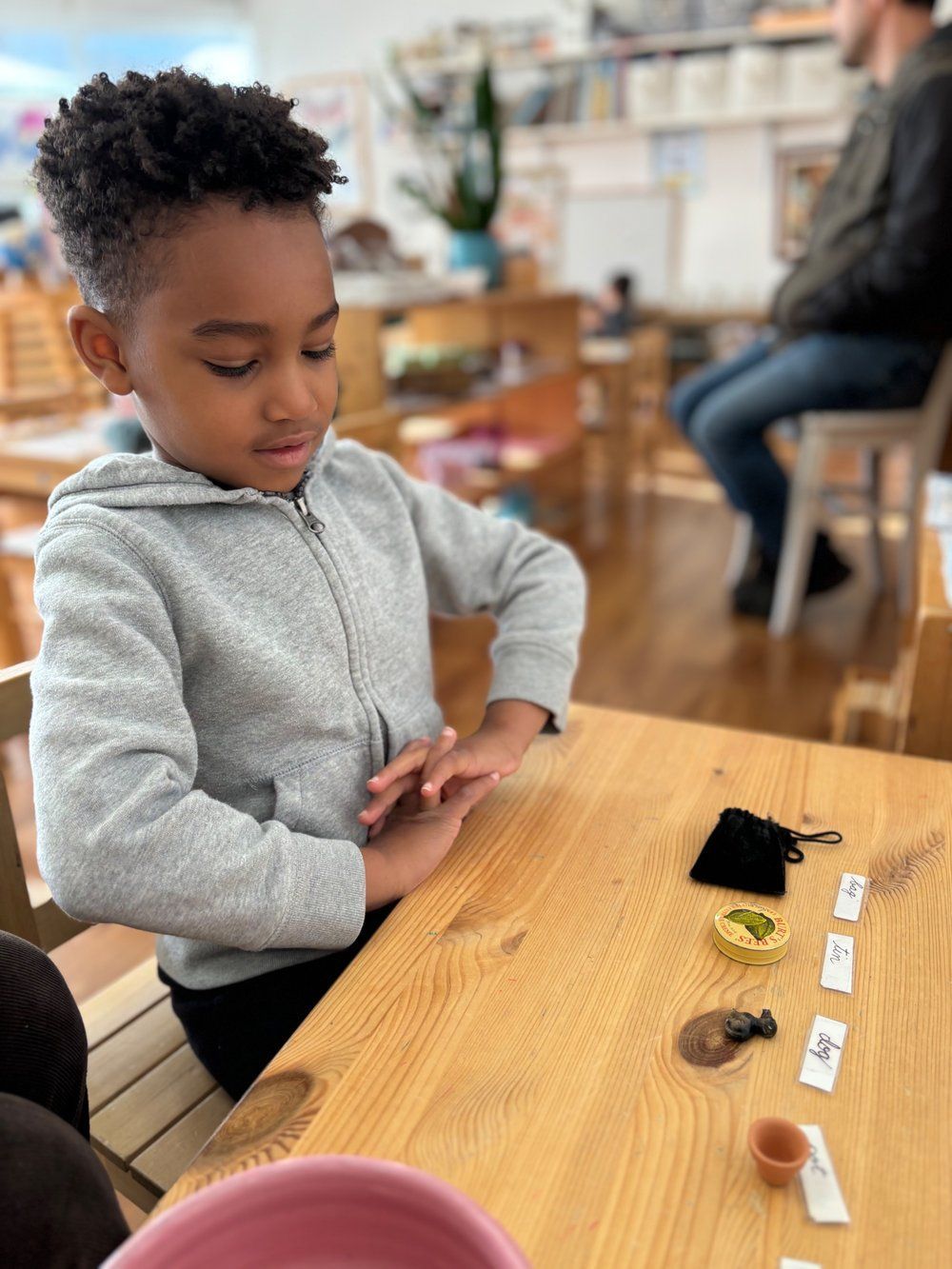 A young boy is sitting at a wooden table playing with toys.