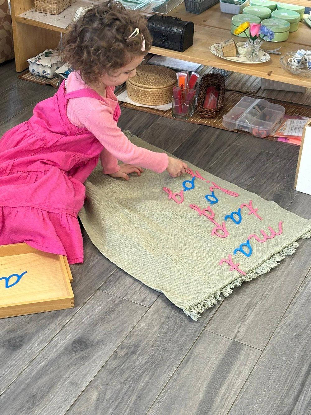 A little girl is sitting on the floor playing with letters on a rug.